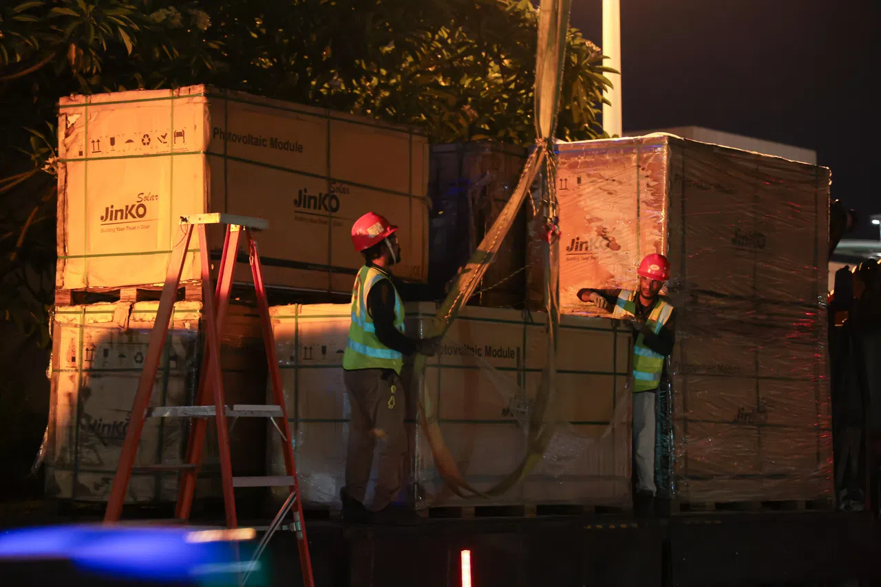 工作人员把一箱箱的太阳能板系在起重臂。（李冠卫摄）