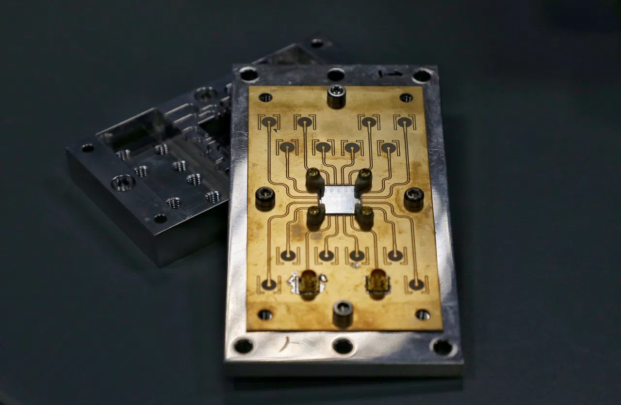 由量子科技研究中心科研人员研制、需要在接近零下273摄氏度环境内运作的量子晶片，晶片主体位于中心方形位置，与其相连的上下16个“圆点”，通过外部蓝色电缆，从量子控制器接收电磁波，实现量子计算。（何炳耀摄）