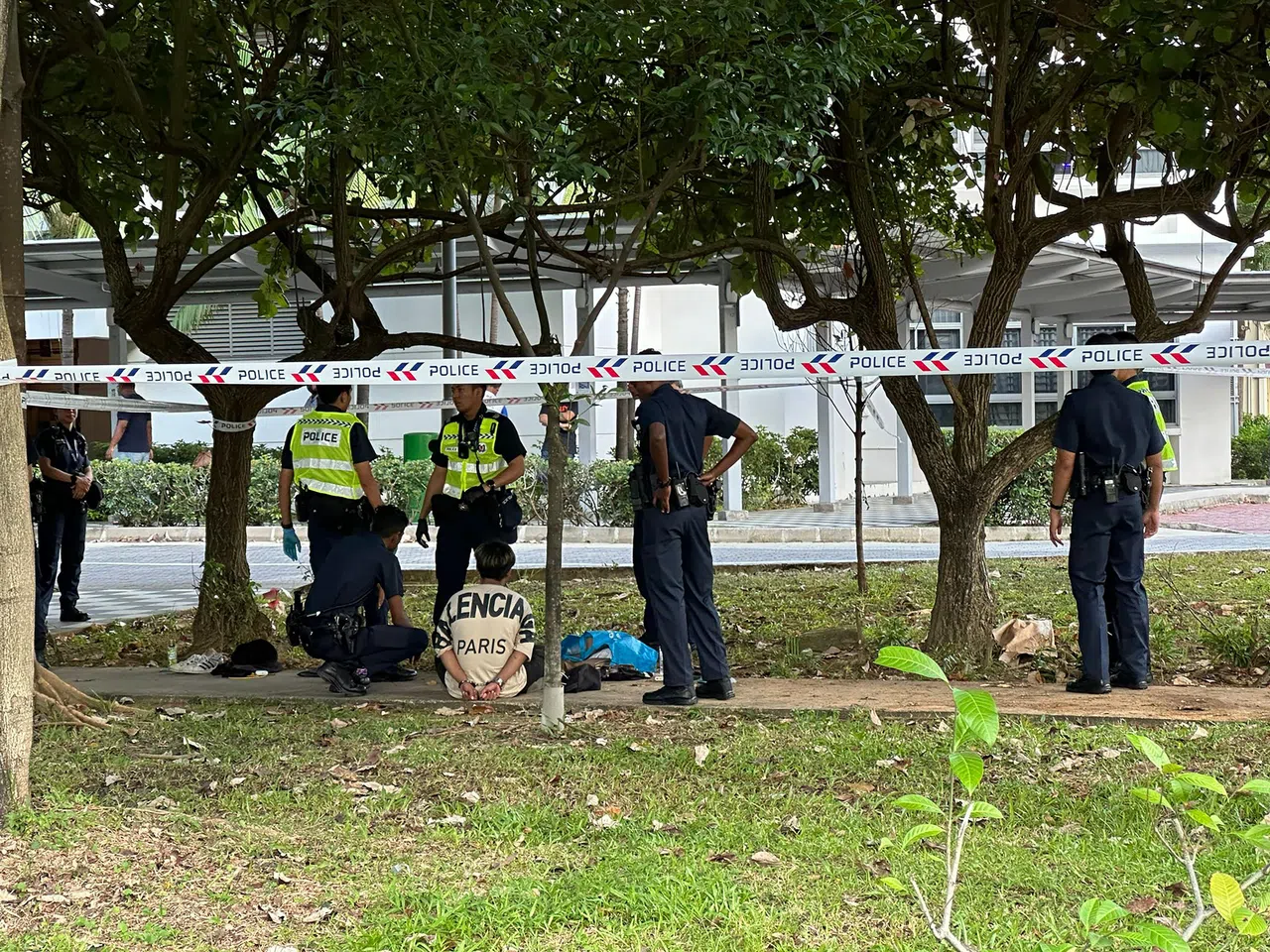 车中年轻男子坐在地上被警方问话。（读者提供）