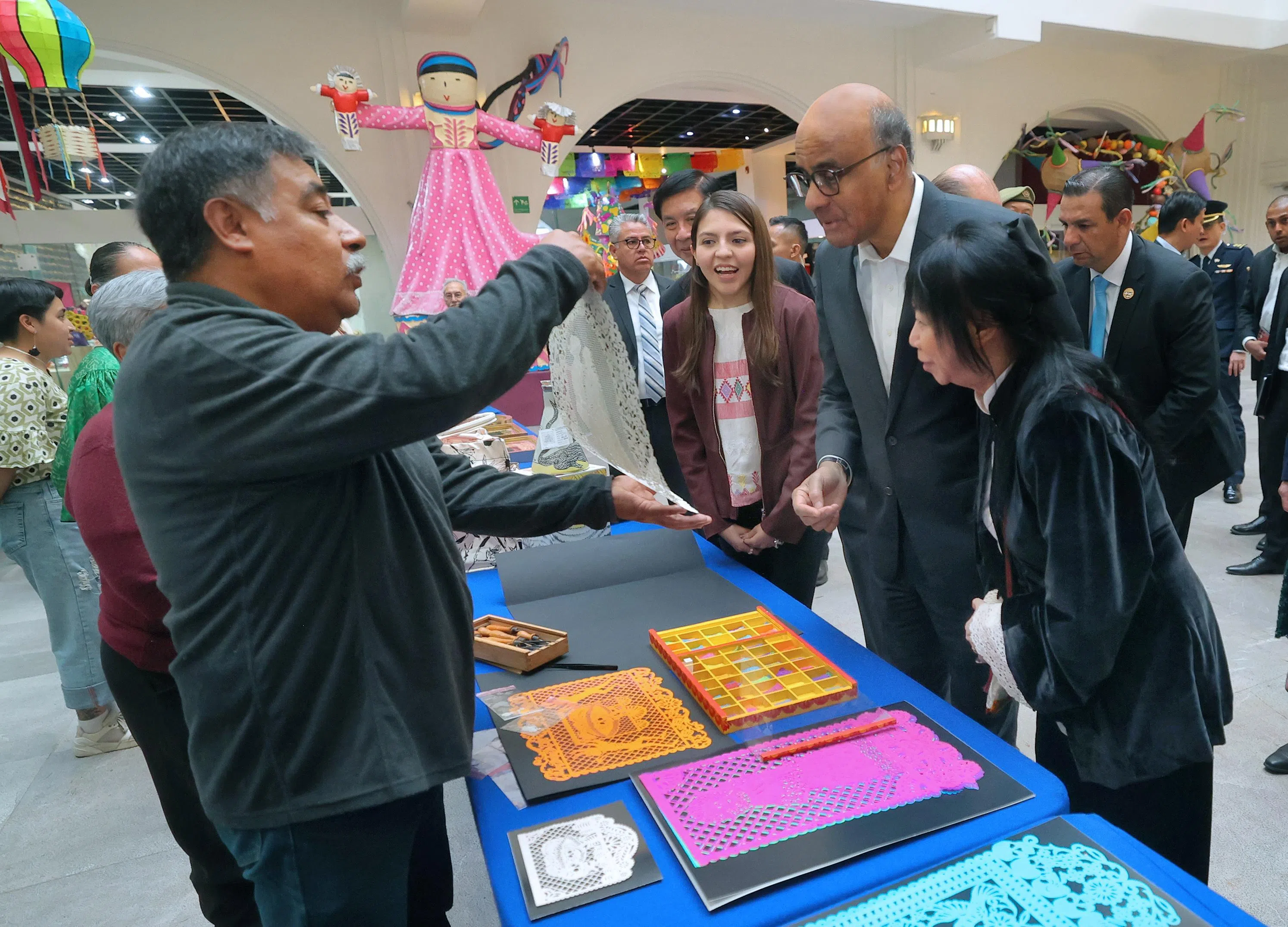 尚达曼总统（右二）和夫人珍一藤木（右一）在墨西哥民间艺术博物馆向艺术家（左）了解纸雕工艺品的制作情况。他后来也向艺术家购买了几件纸雕饰品。（数码部提供）