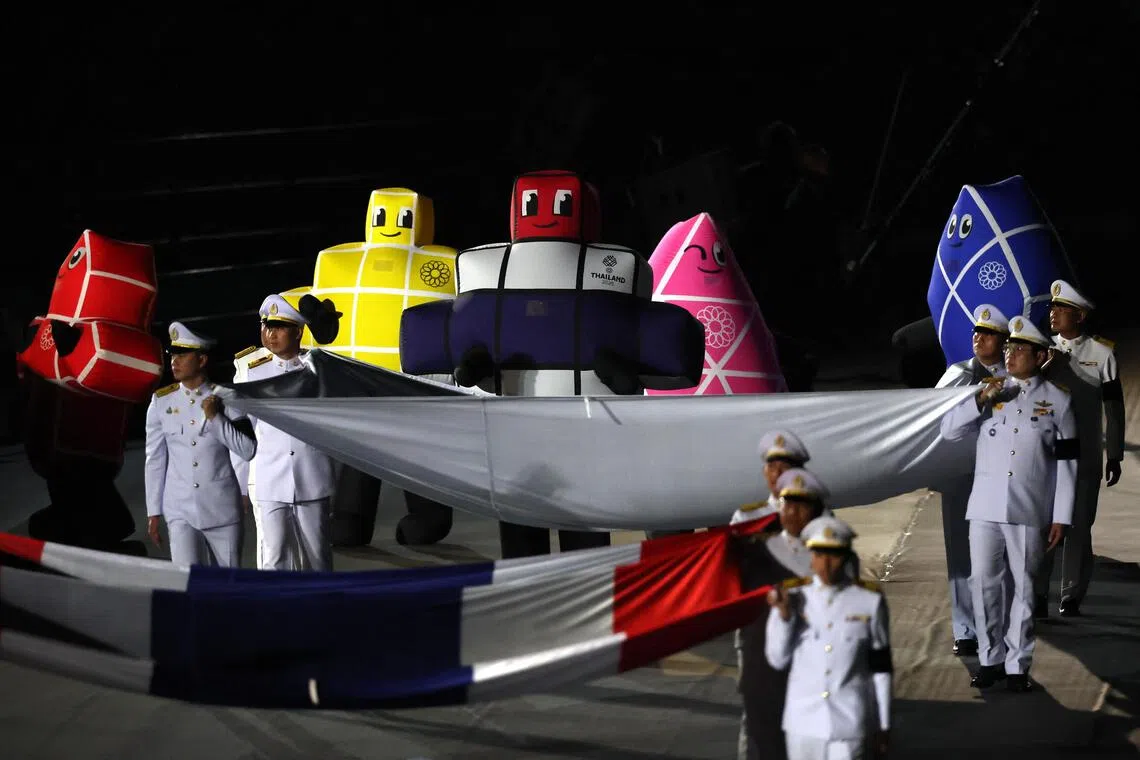泰国军人手举着泰国国旗和赛会旗帜入场，身后则是本届东运会的吉祥物“The Sans”。（路透社）