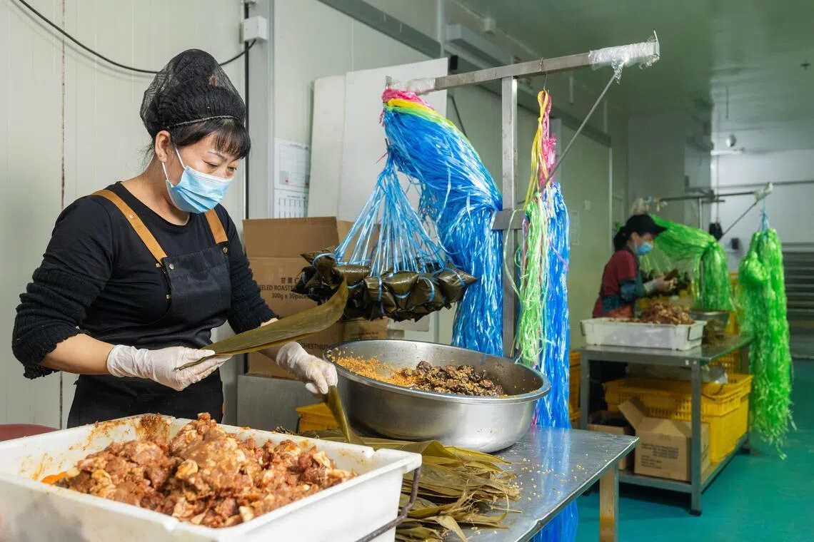 端午节前夕，Yummy Singapore的员工在勿洛食品城四楼的中央厨房赶制粽子，并用不同颜色的粽绳区分粽子口味。（吴先邦摄）