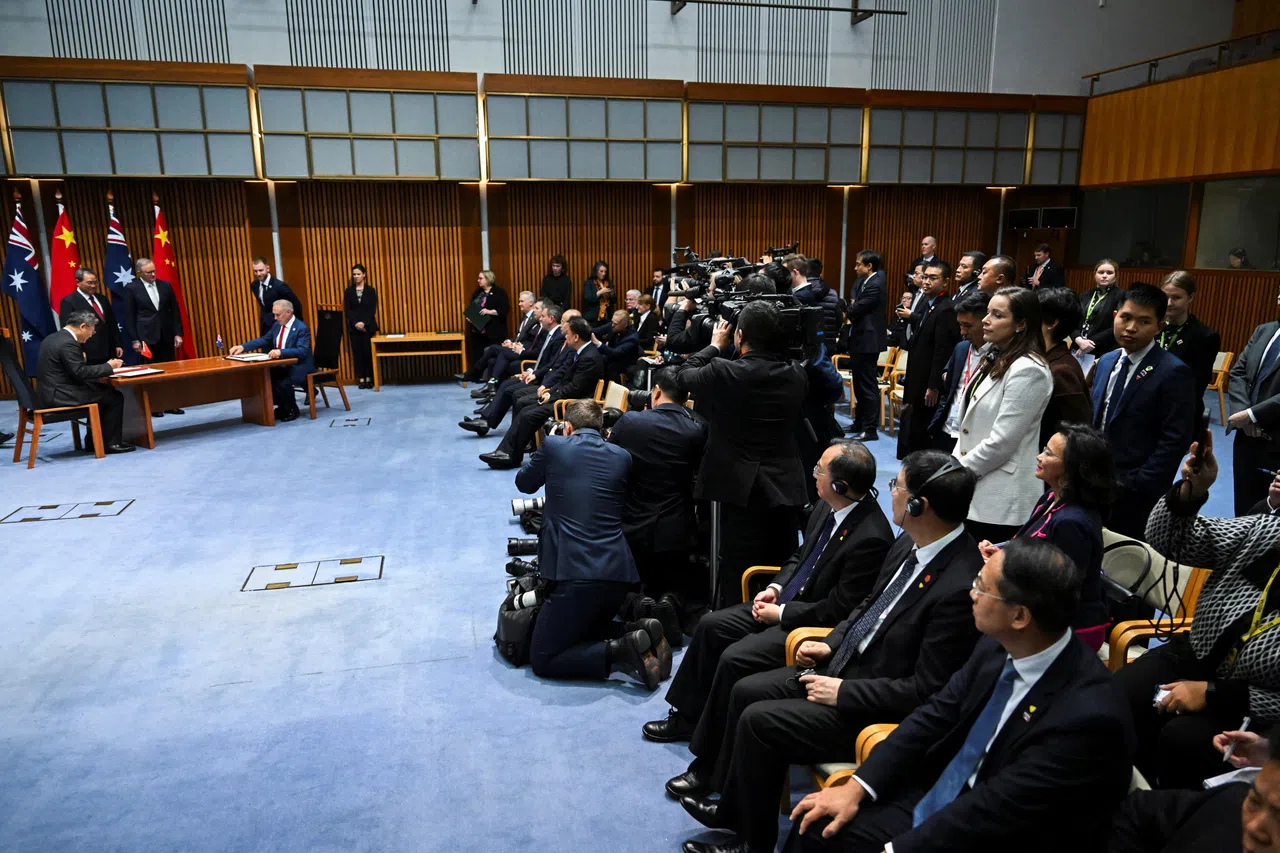 成蕾（坐在图右后排者）6月17日以澳洲天空新闻记者的身份现身中澳合作文件签署仪式现场媒体区，一度疑遭两名中国官员阻挡，引来澳洲官员（白衣站立者）干预。（路透社）