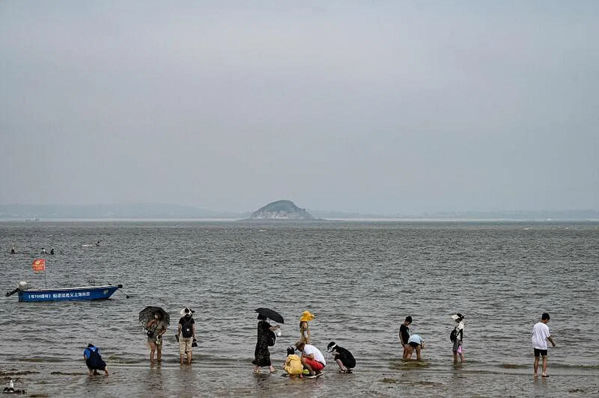 厦门民众在可遥望金门的一处沙滩上嬉水玩乐。（法新社）