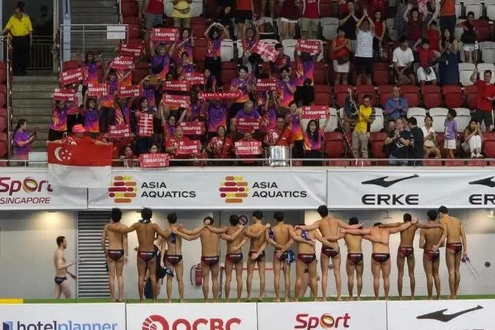 虽然我国U20水球男队（下）经过奋战后不敌伊朗，但尼拉团队成员（上紫衣）还是在赛后继续为健儿们加油打气。（新加坡泳联档案照）