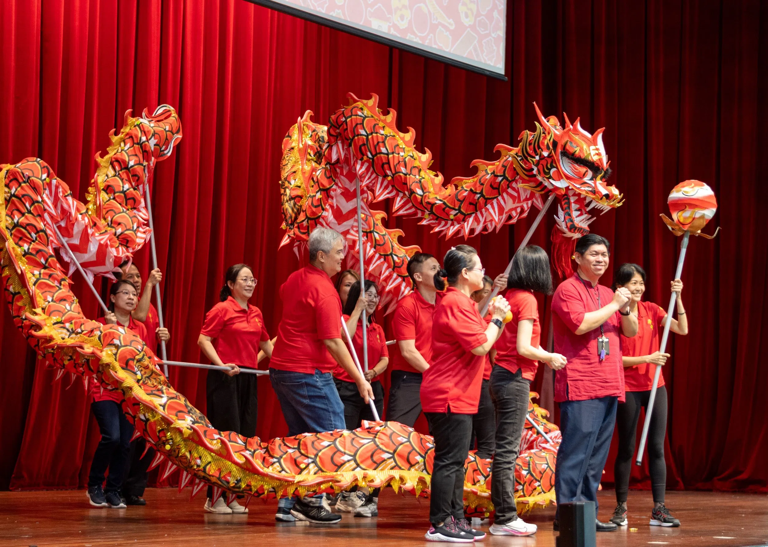 李白彬校长（前）上台与表演舞龙的家长一同庆贺新年。  （庄燊磊摄）