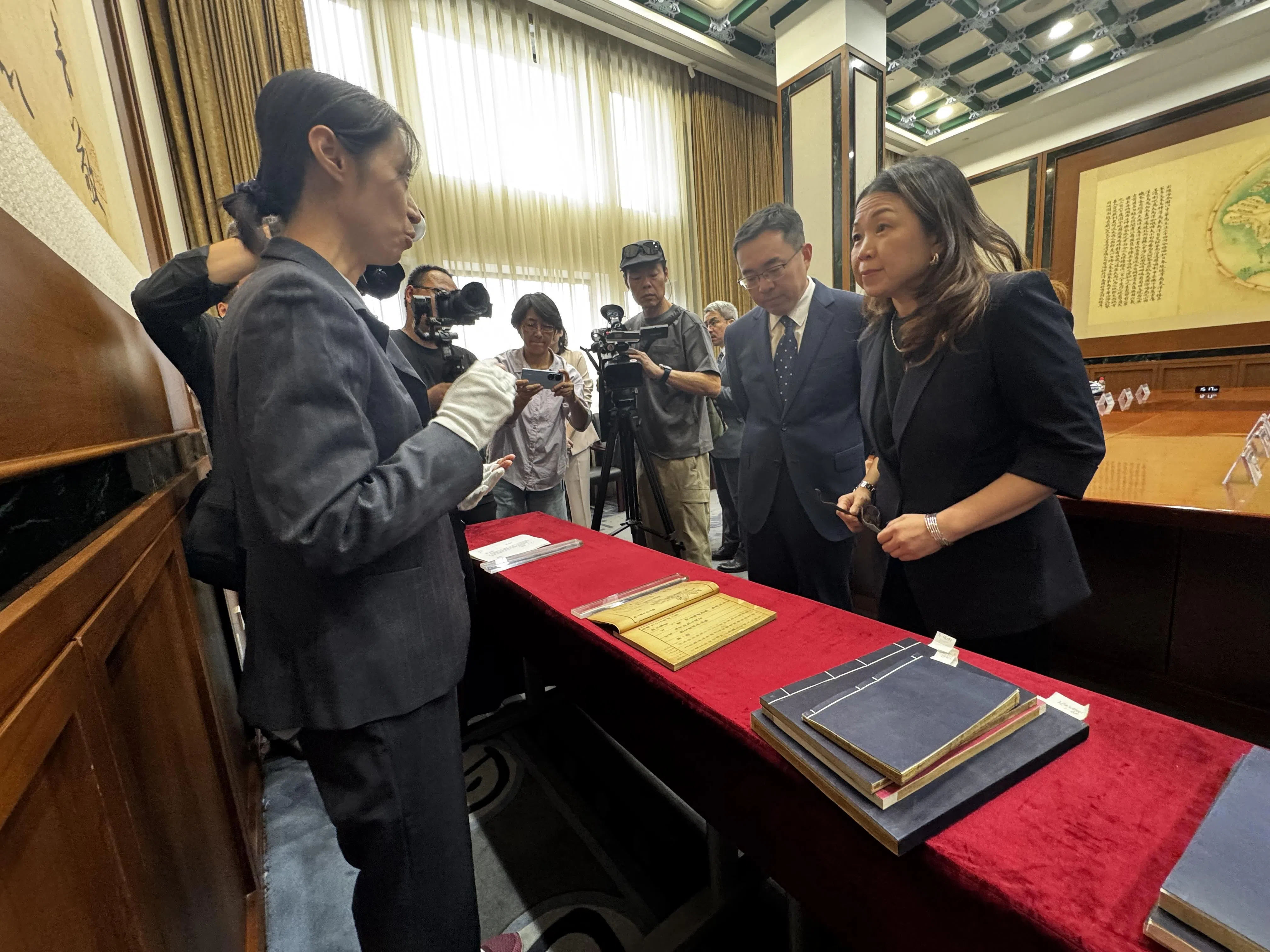 新加坡国家图书馆管理局总裁谭丽娟（右一）和中国国家图书馆副馆长魏崇（右二）星期天（9月20日）在北京的中国国家图书馆，聆听讲解员李文洁（左一）介绍即将到新加坡展出的古籍。（沈泽玮摄）