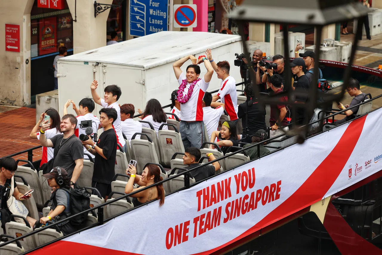 巴士在经过牛车水时，墨士廉向支持者比心。（何家俊摄）