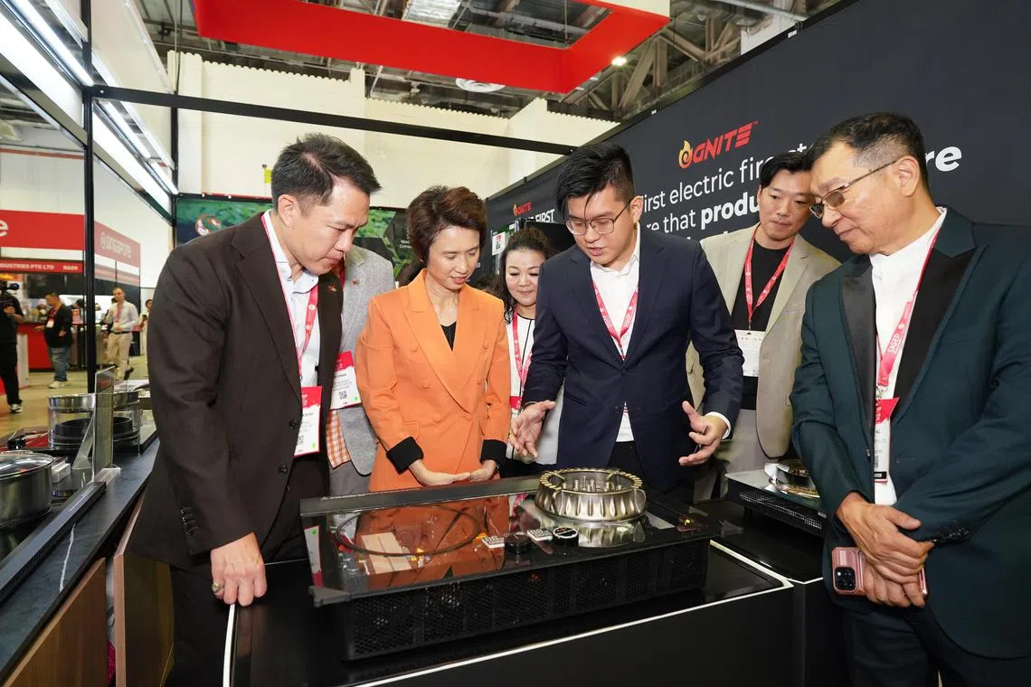 贸工部兼文化、社区及青年部高级政务部长刘燕玲（左二）在新加坡餐饮业协会会长莫斯翔（左一）等主办方人士陪同下， 参观烹饪设备制造商Yumiko Pte Ltd的展位。（主办方提供）