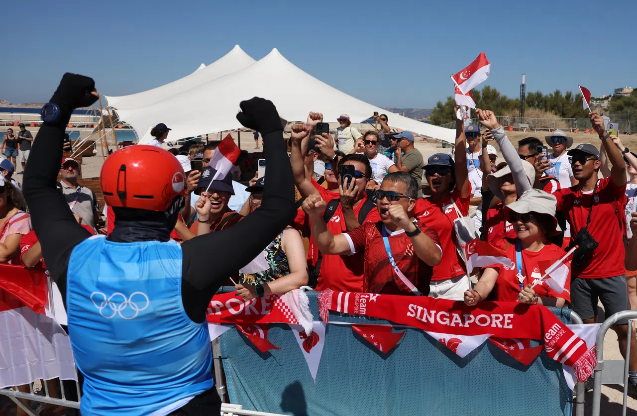 包括唐振辉（中间红衣戴墨镜者）部长在内的我国支持者，在赛前为墨士廉打气。（新加坡体育理事会提供）