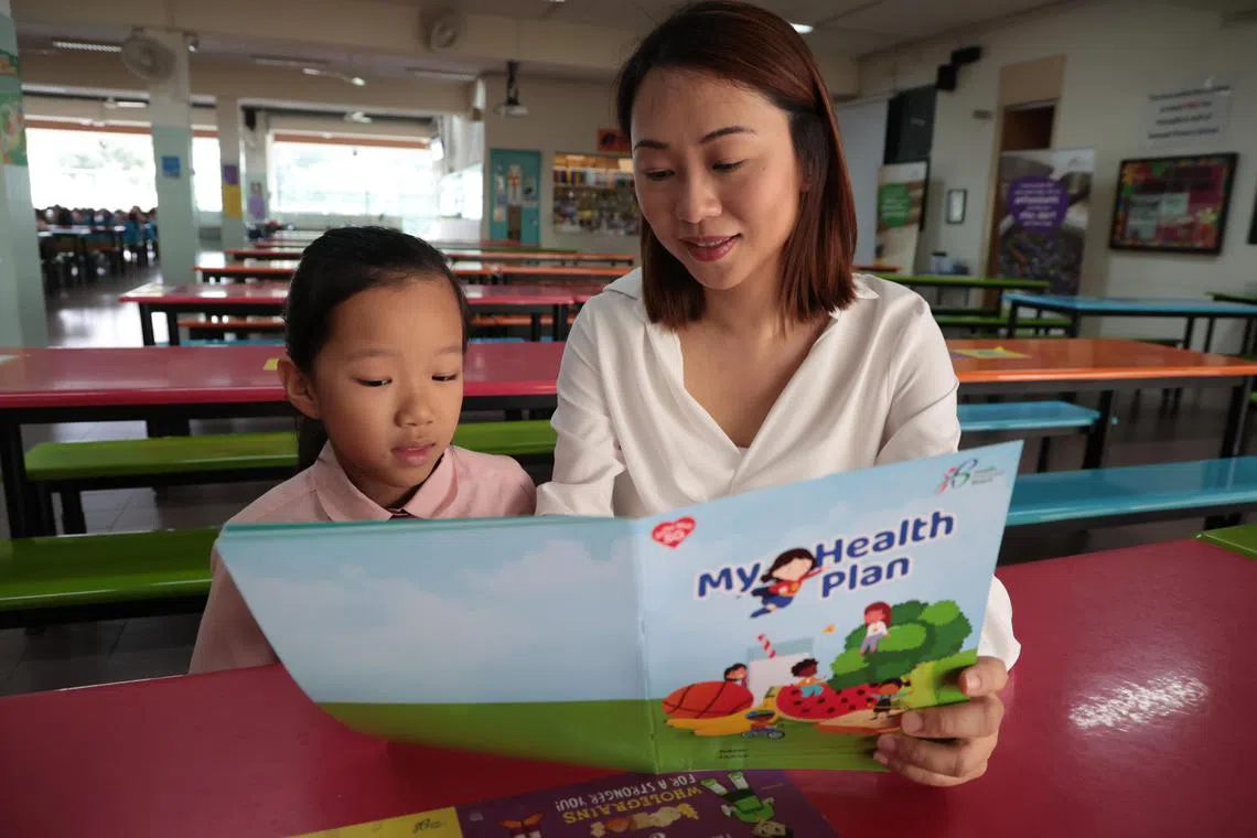 家长罗雯绮（右）利用保健计划的机会，向女儿王佳钰灌输健康生活的概念。有关计划的学生册子附上运动贴士等互动单元，鼓励学生完成。（梁麒麟摄）