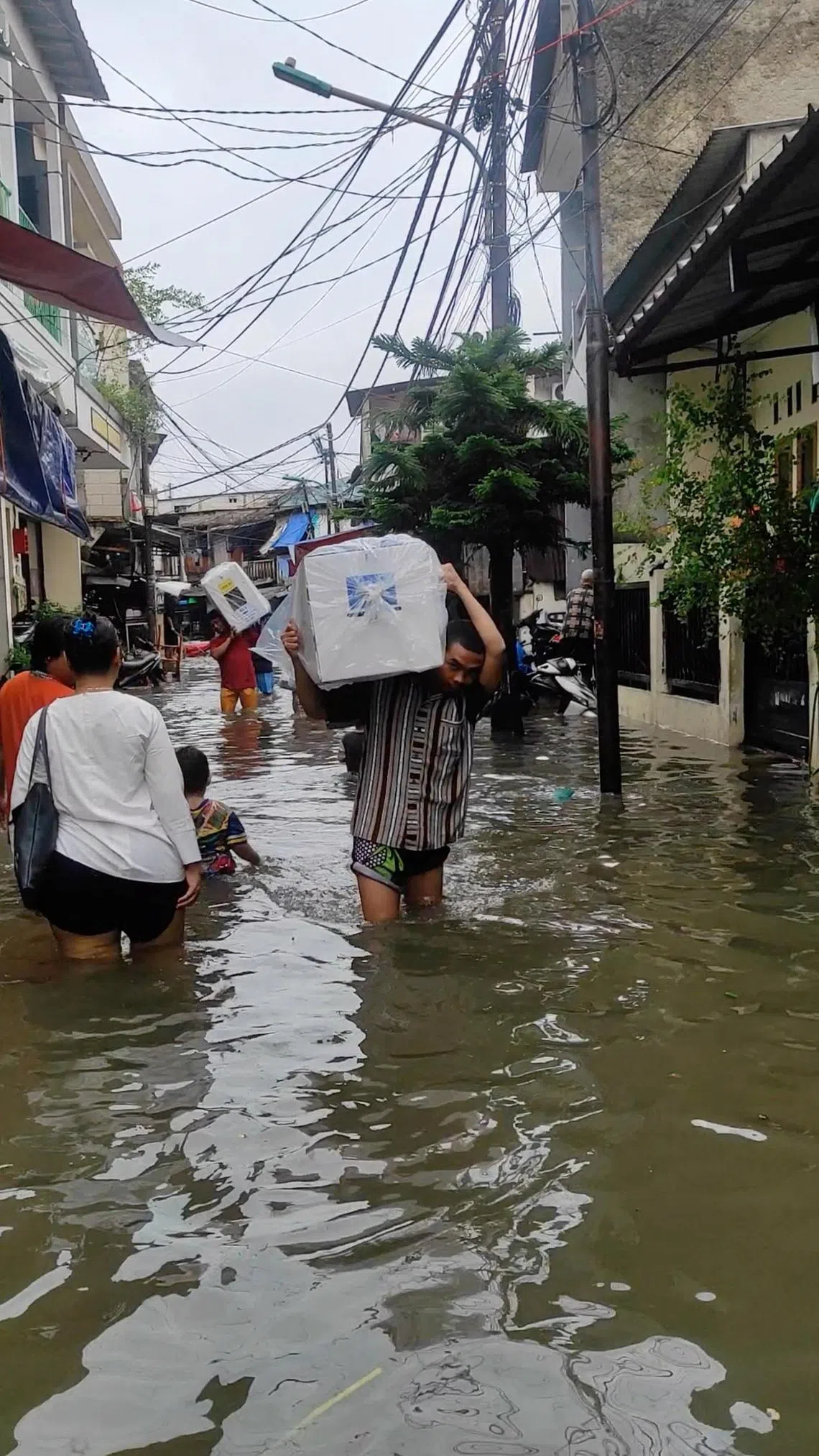 雅加达星期三清晨下了一场大雨，雅加达一些地方发生洪水，投票站职员扛着票箱涉水而过。（路透社）
