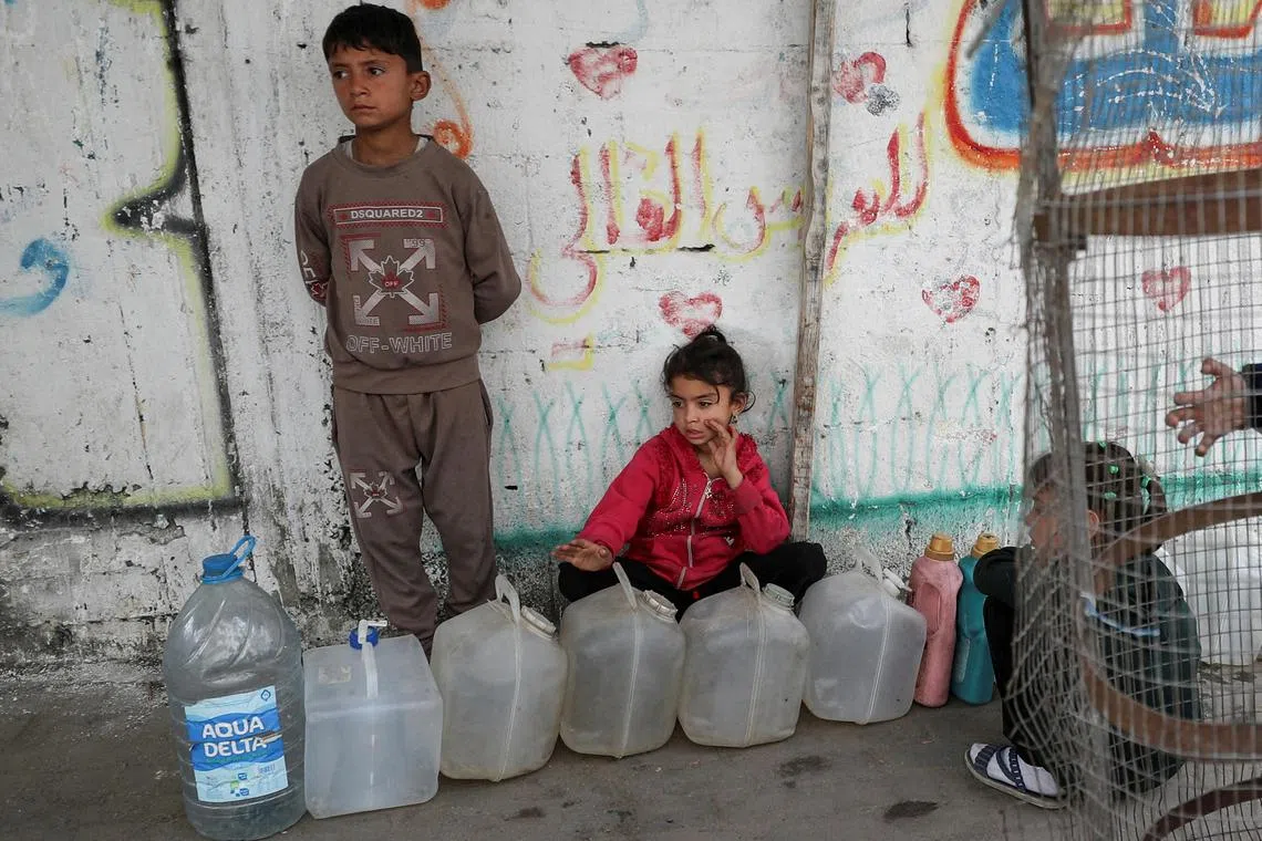 4月6日。加沙市的几个巴勒斯坦孩童守着装水的容器。（路透社）