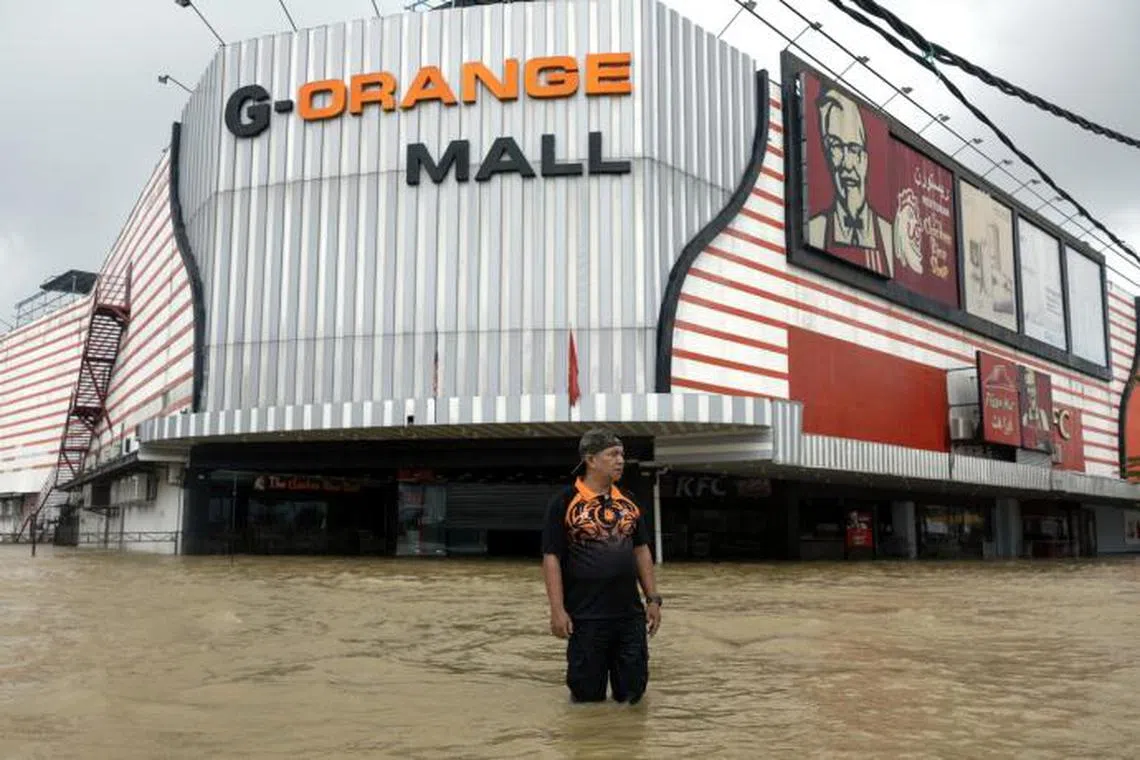 目前马来西亚共有六个州属受到水灾影响，丹州几乎全面沦陷，图为居民在购物中心前涉水而过。（南洋商报）