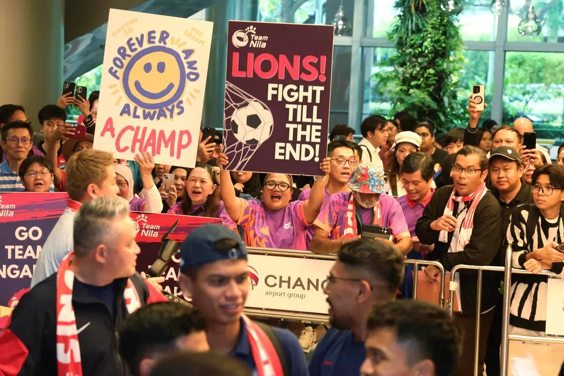 樟宜机场人山人海，球迷们举牌欢迎雄狮队凯旋而归。（郑一鸣摄）