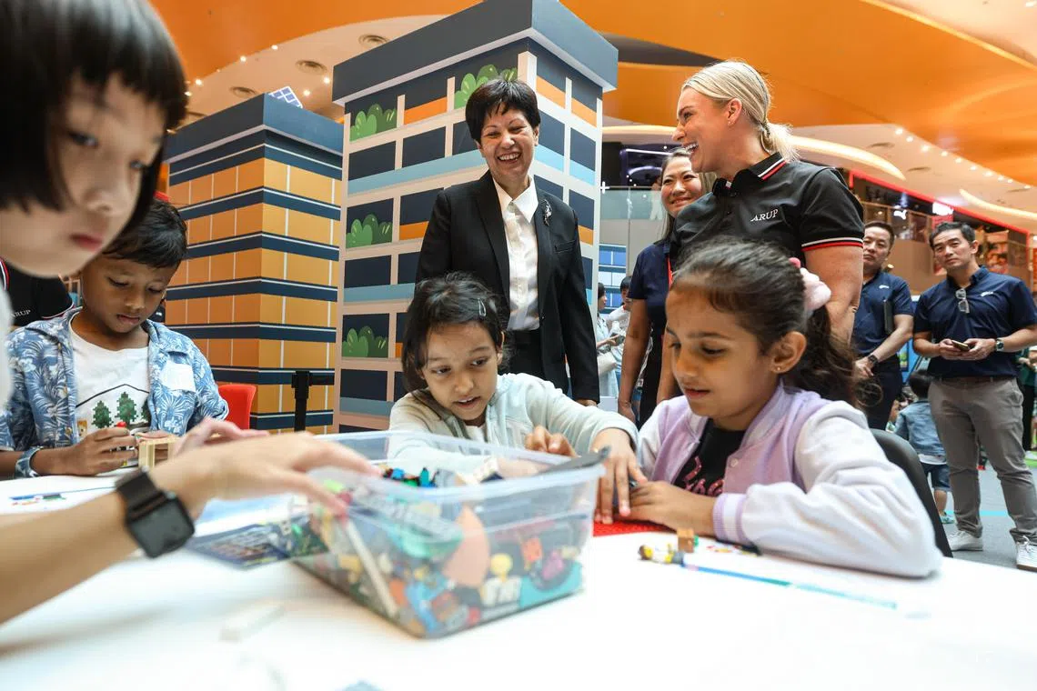 总理公署部长兼财政部及国家发展部第二部长英兰妮（黑色外套），也是建筑设计和工程顾问工作小组的联合主席。她星期五到怡丰城出席首届“建设新加坡节”并参观展位，观察小朋友如何利用积木发挥创意。（关俊威摄）