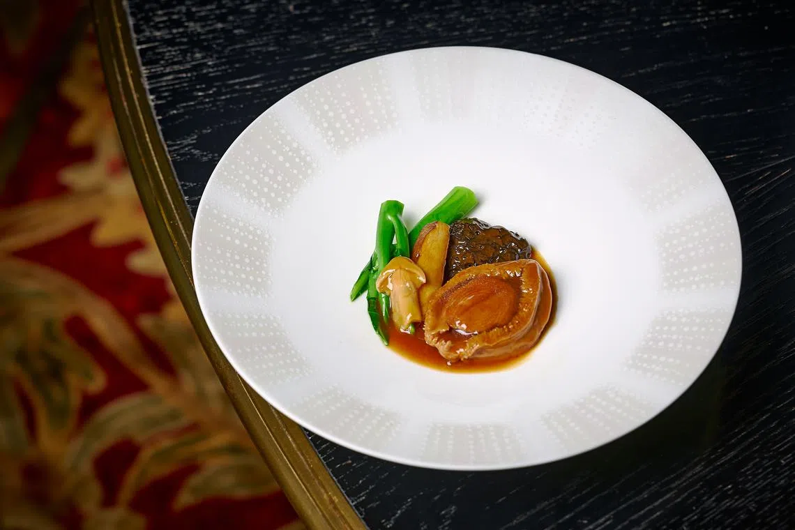 山珍汁十六头南非鲍鱼，一改平日红烧鲍鱼的做法，以三种不同菌类制作酱汁。（餐馆提供）