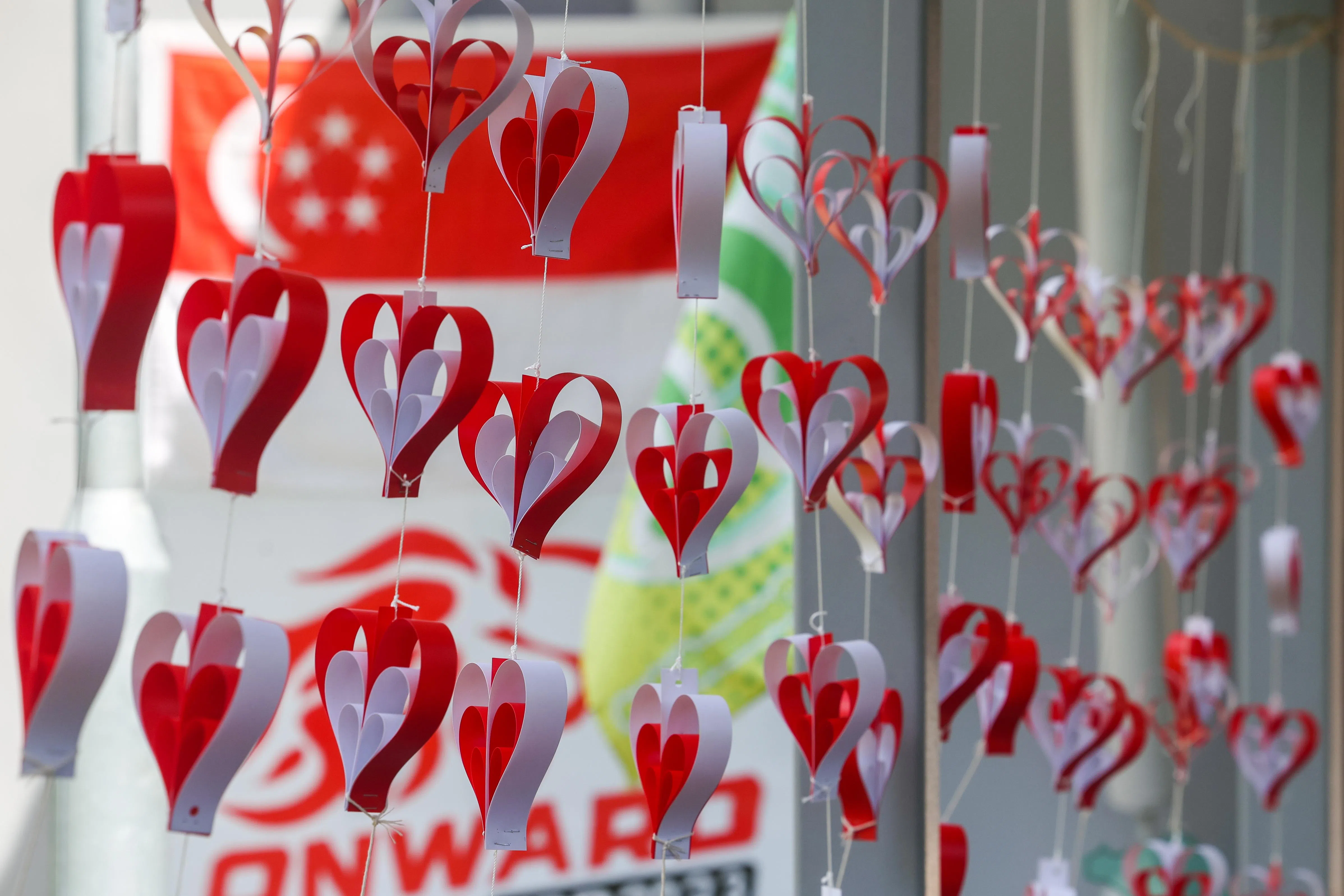 蔡厝港北第787座组屋的国庆装饰别出心裁，用红白两色制成心形吊饰悬挂在走廊，代表人们齐心协力共创未来。（陈斌勤摄）