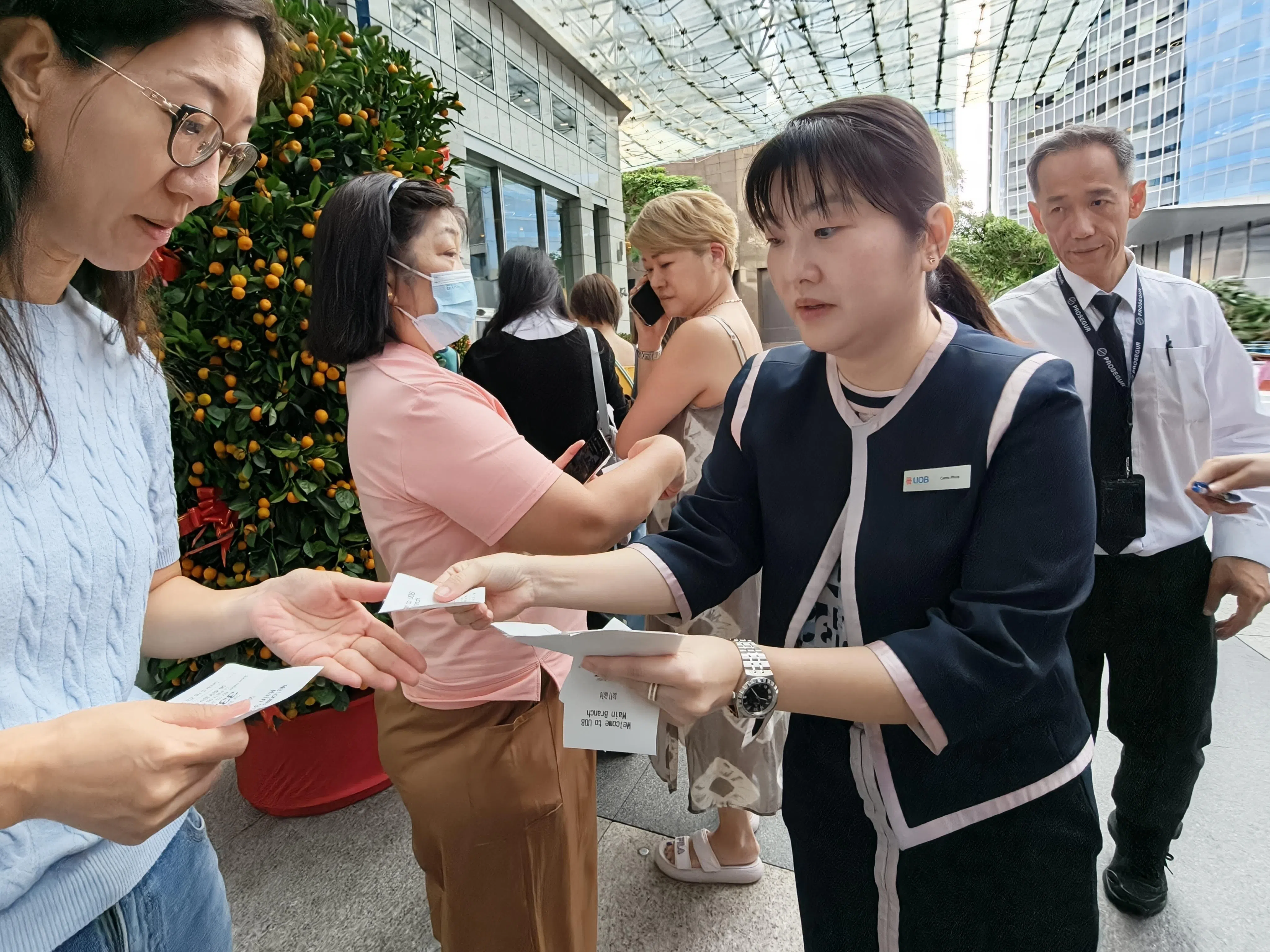 银行职员向排队买金的公众派号码。开门营业前，已有60多名顾客在等候。（何家俊摄）