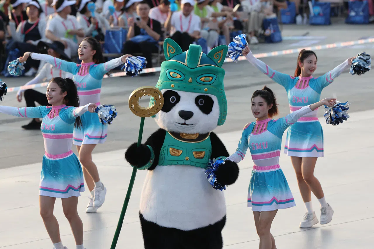 融合了熊猫和三星堆元素的成都世运会吉祥物“蜀宝”（中）与啦啦队员在开幕式上表演。（路透社）