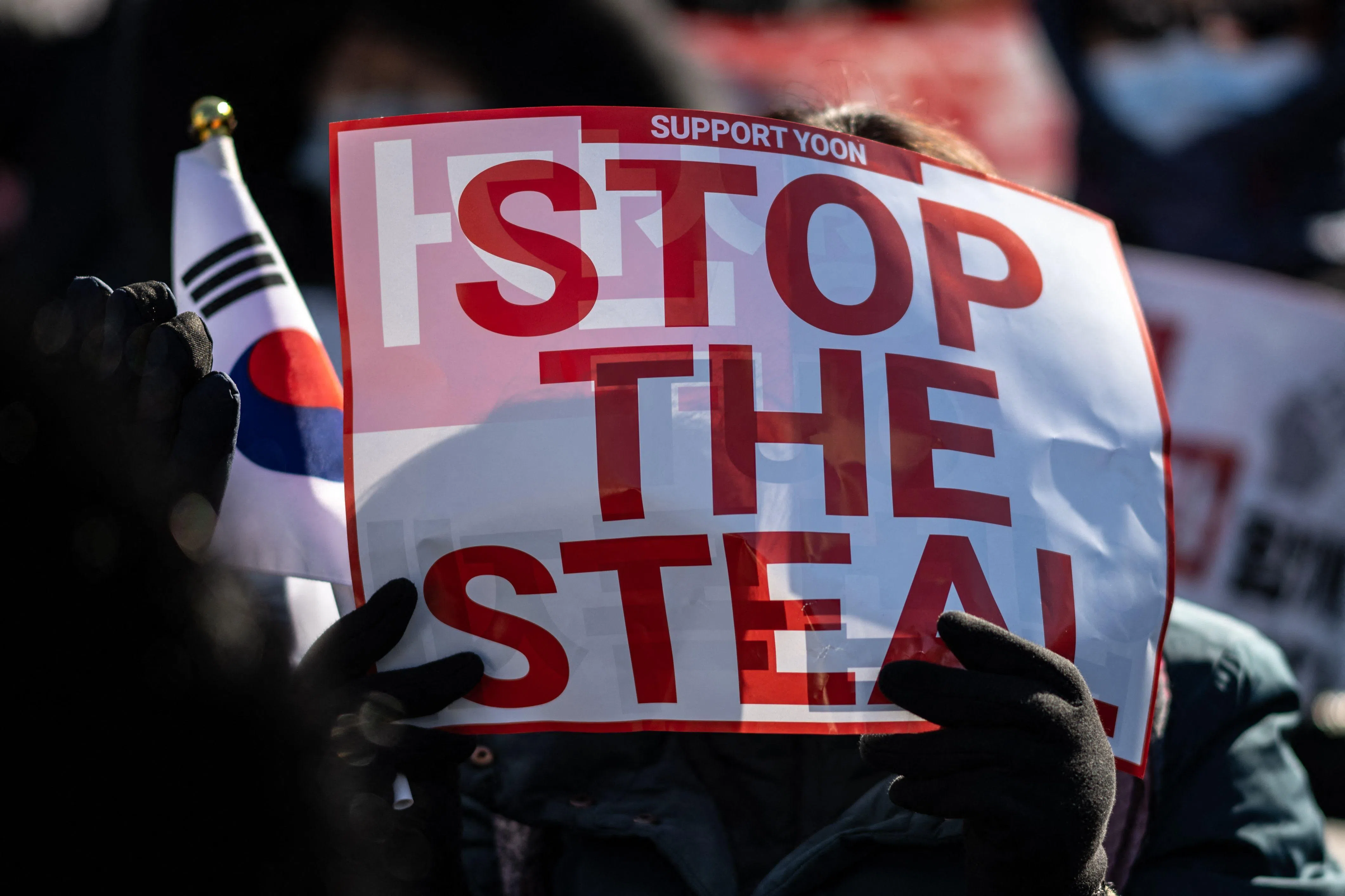 尹锡悦的支持者星期六在首尔光化门举行集会，一名支持者手持美国候任总统特朗普常用的口号“阻止偷窃”。（法新社）