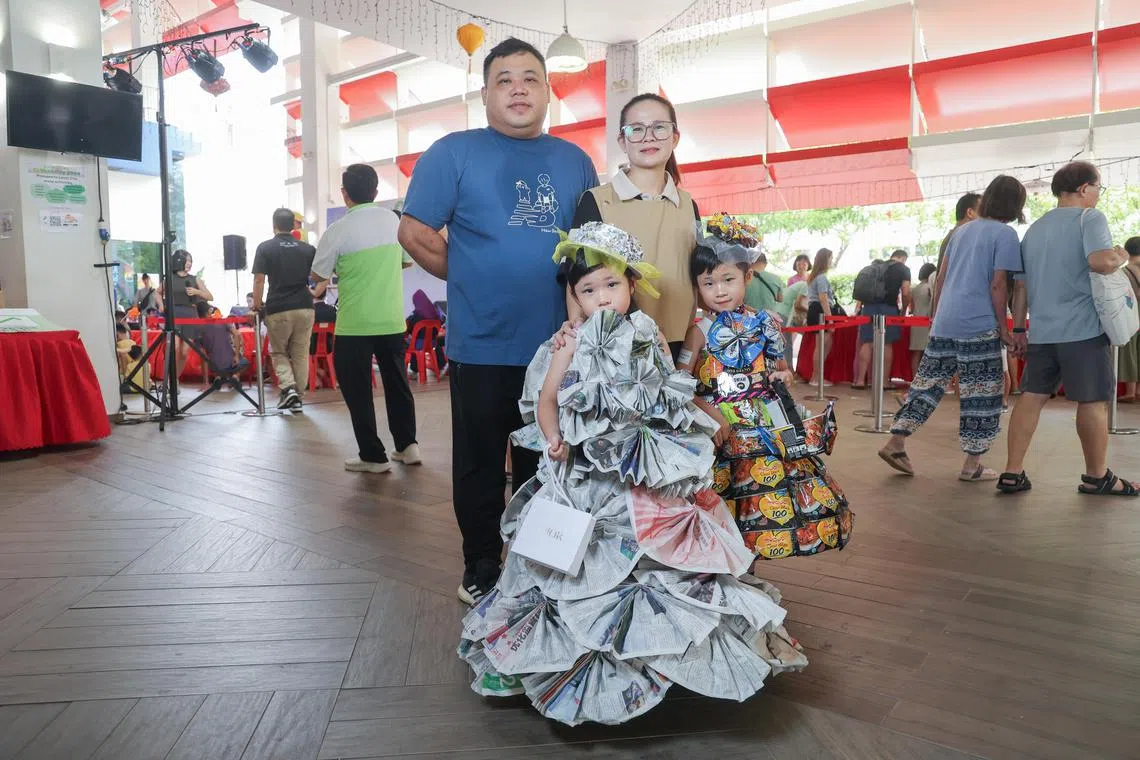 符云（后排右）与丈夫和女儿一起，利用快熟面包装袋、零食袋和旧报纸等回收材料，设计礼服和配饰。两个双胞胎女儿星期天在茨园日上走秀，展示一家人的作品。（吴先邦摄）