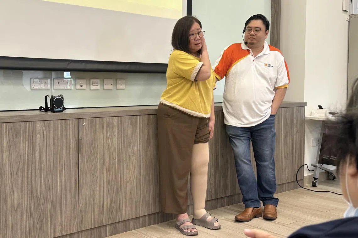 曾接受黄伟杰医生治疗淋巴水肿的女患者拉起长裤，让大家看她那肿胀受到控制的左脚。（李亦筠摄）