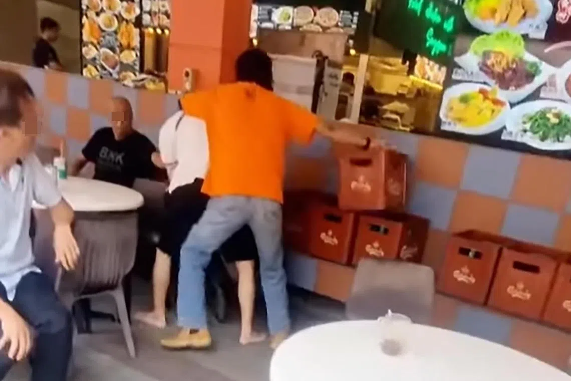 橙衣男将白衣男按到墙角。（取自网络）