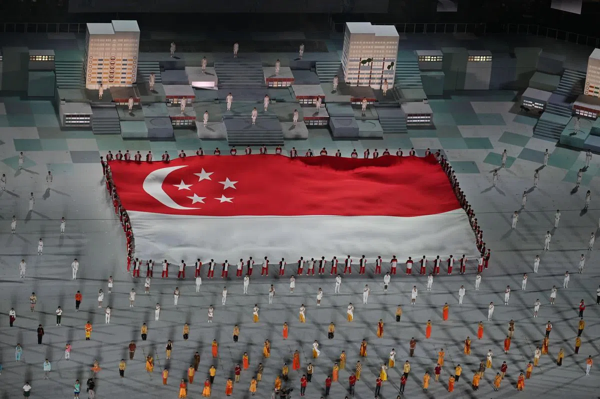 庆典结尾时，表演者举起巨型国旗，全体观众庄严地唱国歌和宣读信约。（唐家鸿摄）