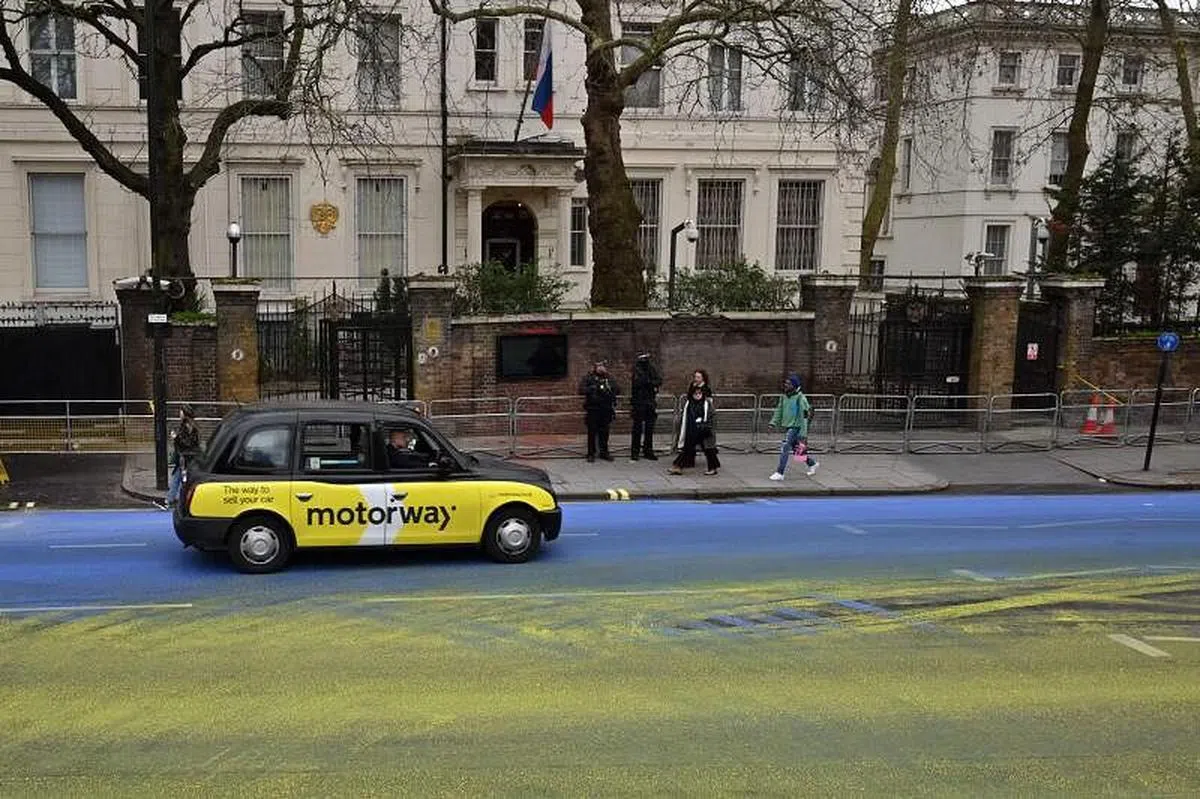 俄罗斯入侵乌克兰一周年前夕，英国一群活动人士在俄罗斯驻伦敦大使馆外的道路上，倾倒了数百升黄色和蓝色油漆，绘制成一面巨大的乌克兰国旗。（法新社）