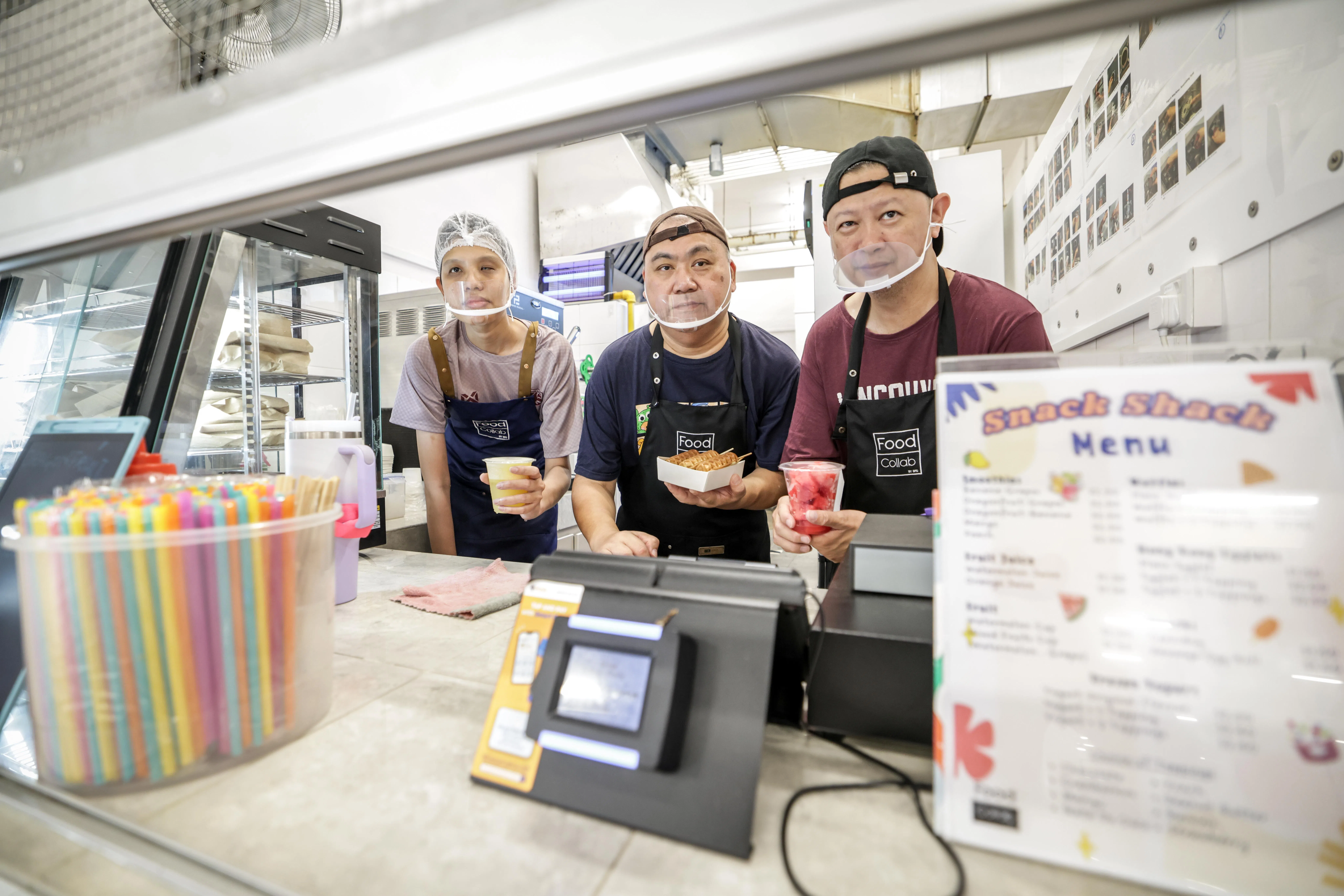 菲尔道斯（左）和中风康复者陈楚藤（右）是其中两名在国专长老会中学食堂工作的特需者。另一名中风康复者吕家福在另一所学校食堂摊位当管工，趁当天学校居家学习、摊位没开，便到国专长老会中学帮忙。（叶振忠摄）