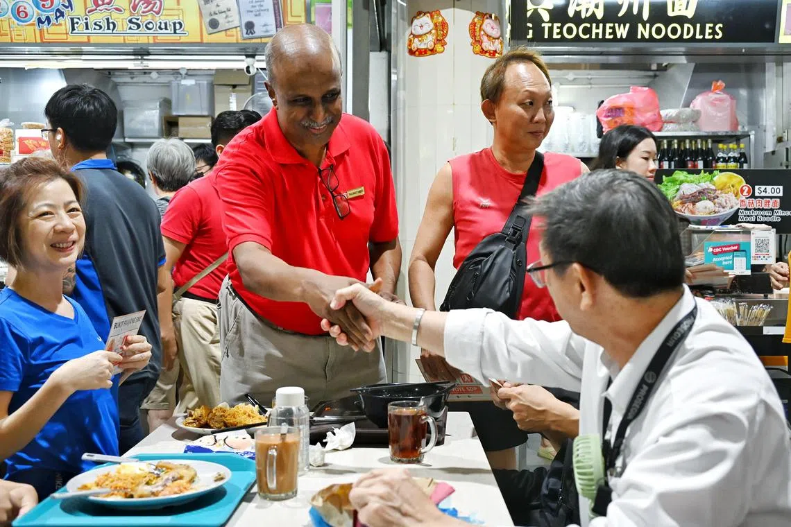 新加坡民主党主席淡马亚教授（中间红衣者）上午走访武吉班让熟食中心，同用餐者交流。（每日新闻）