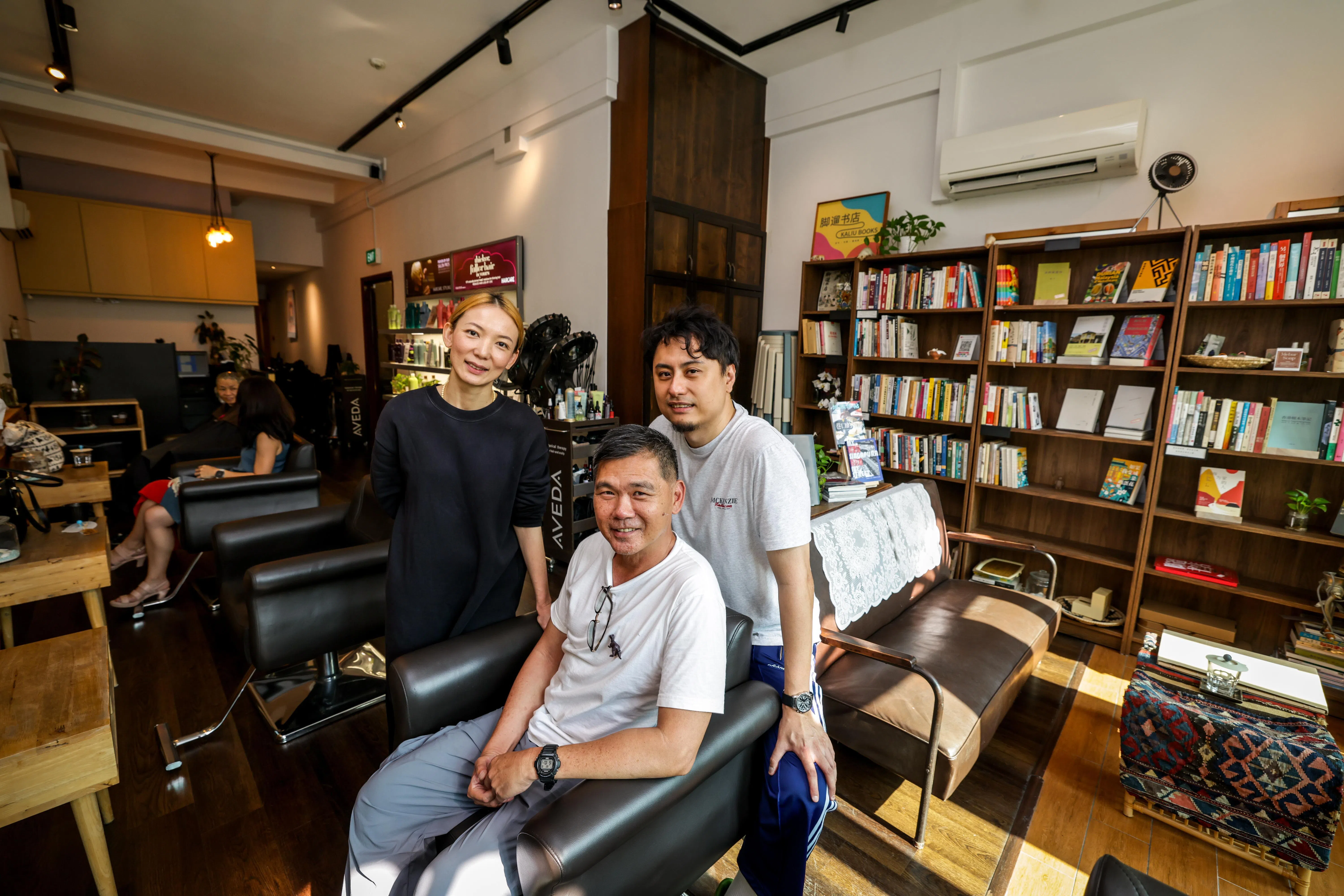 叶孝忠（中）和发廊的两位店主是多年好友。（叶振忠摄）