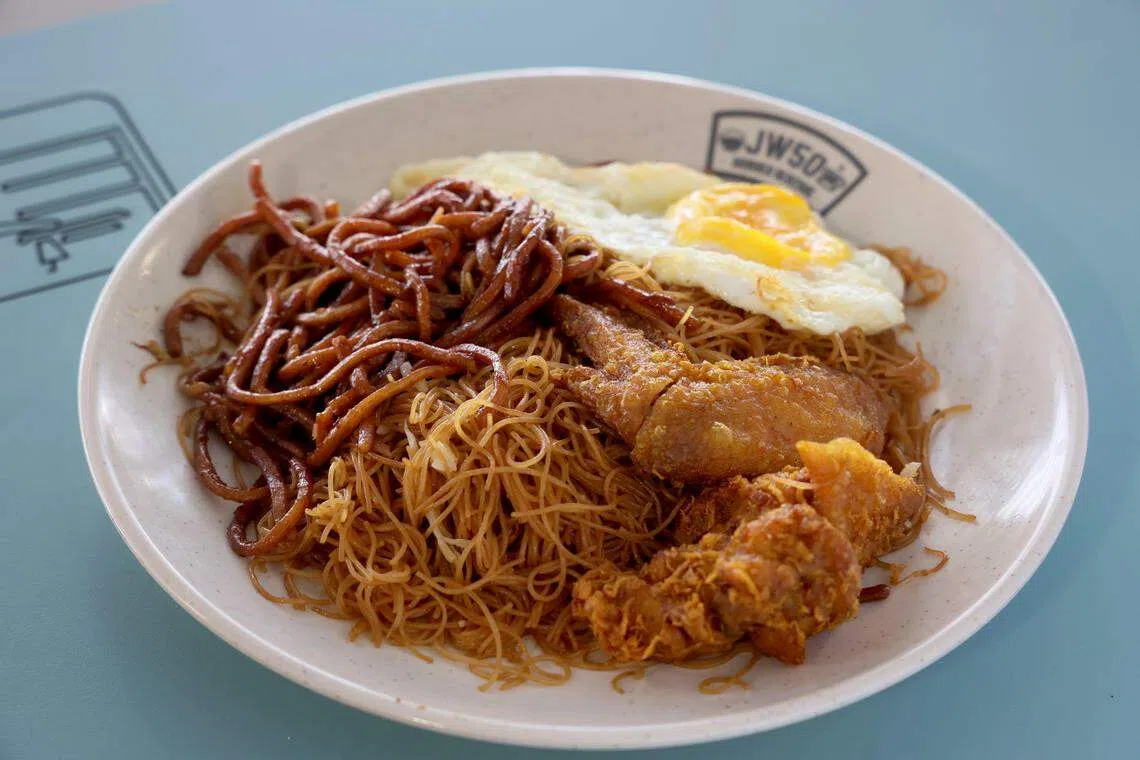 仕银炒米粉.椰浆饭的炒米粉加炒面，配上荷包蛋和炸鸡翅膀，饱足感十足。（龙国雄摄）