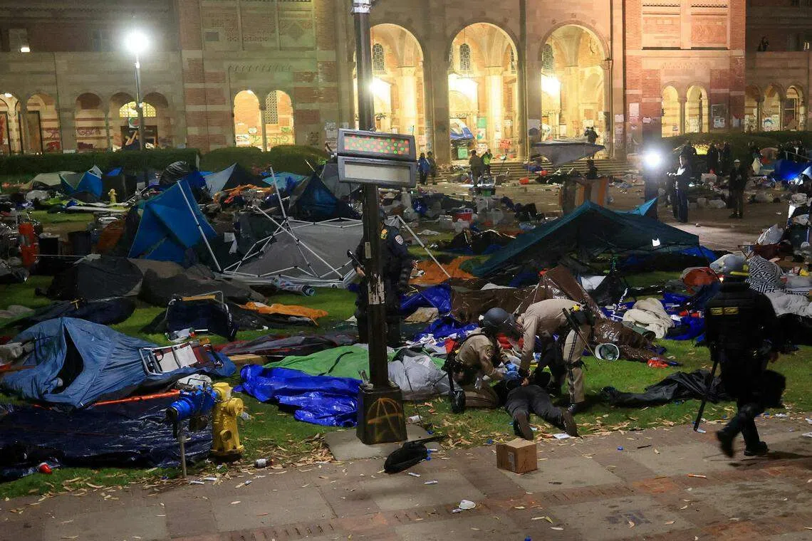 执法人员星期四在加州大学洛杉矶分校强行拆除反以哈战争示威者在校内广场搭建的营地，同时逮捕示威者。（路透社）