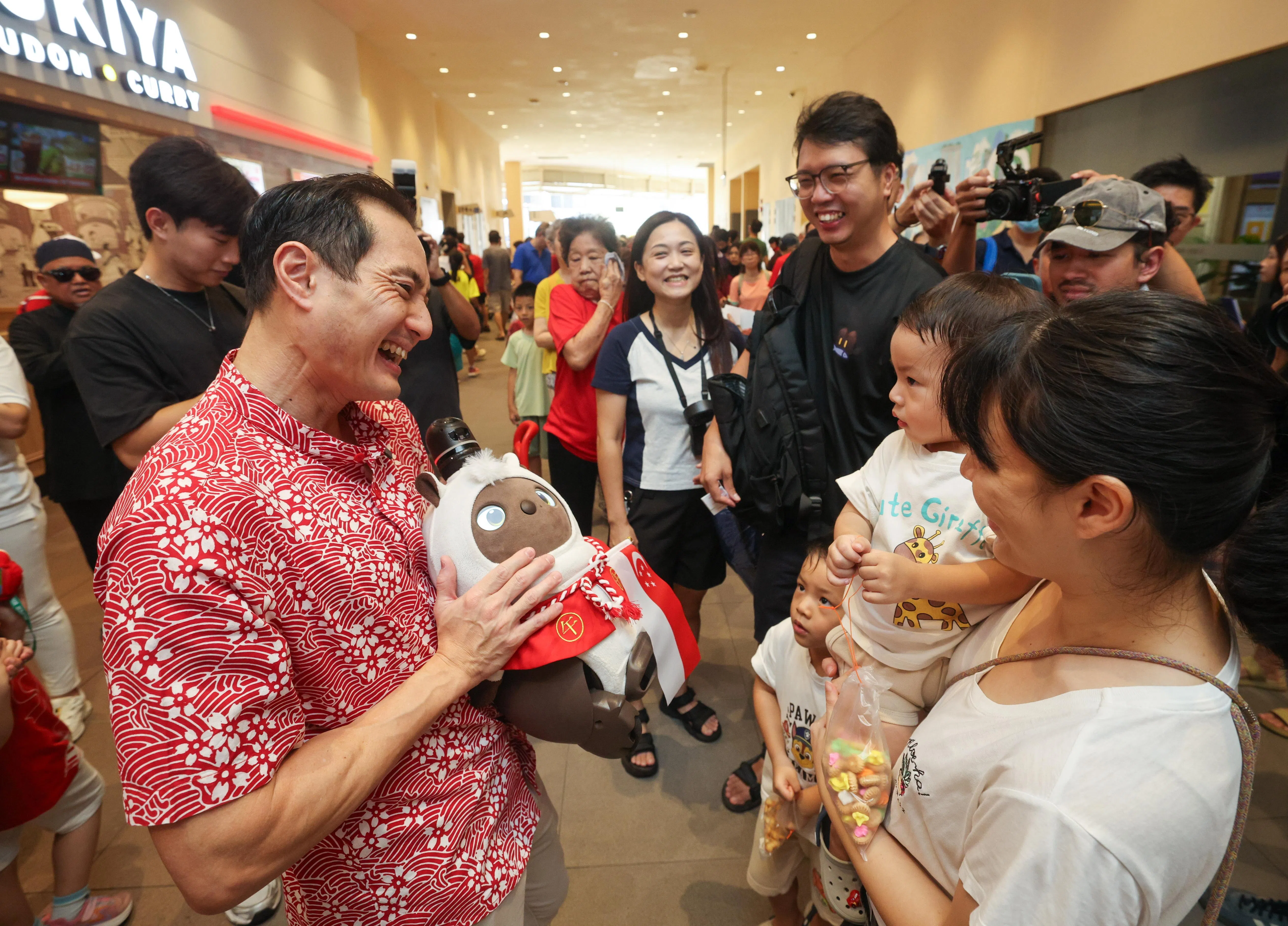 数码发展及新闻部兼保健卫生部高级政务部长陈杰豪指出，甘榜菜市居民有三四成是年长者，“老老照顾”（六七十岁照顾八九十岁）现象普遍，夹在上下两代之间的年轻家庭的照护压力也不小，科技工具可帮上忙。他手里拿着的是日本的智能陪伴机器人，未来菜市区居民也可以申请把这类科技产品借回家试用。（陈渊庄摄）