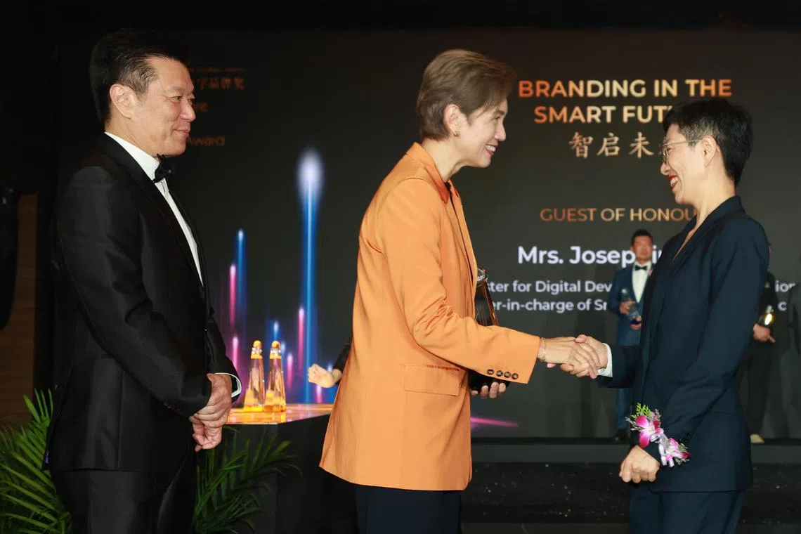 代表Epitex领奖的营销总监徐鑫（右一）上台领奖，与主宾数码发展及新闻部长杨莉明（中）握手。左一是《联合早报》总编辑吴新迪。（邝启聪摄）