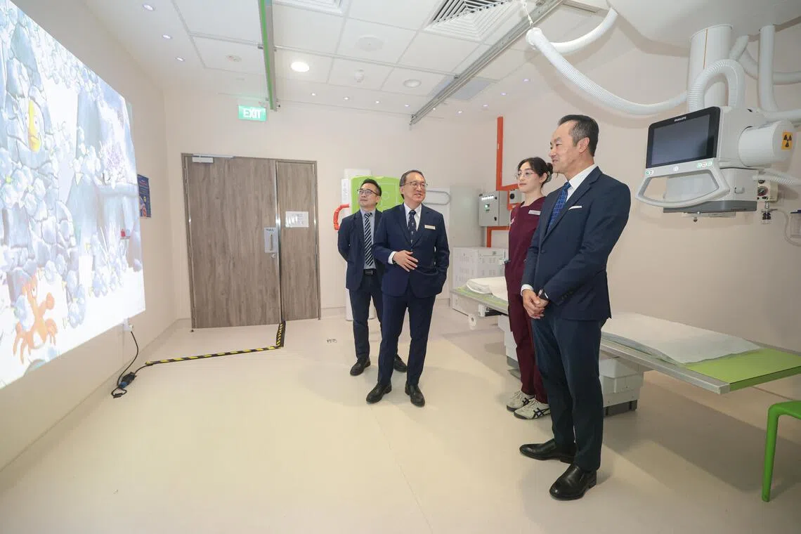 卫生部兼人力部高级政务部长许宝琨医生（右一）星期一走访国大医院骨科外科中心，骨科外科主任兼高级顾问医生许海波教授（左二）向他介绍新设施，包括X光检查室内有动画投影，可让儿童病患放松心情。（李冠卫摄）