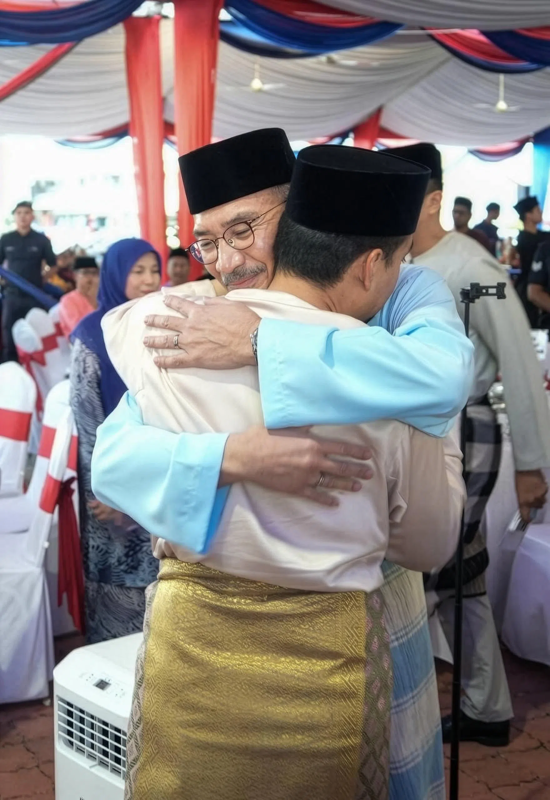 希山慕丁（面对镜头者）与外甥翁哈菲兹在开斋活动上拥抱问候。翁哈菲兹也是柔佛州务大臣，他星期五特地到希山慕丁的国会选区参加开斋活动，被视为力挺舅舅重返巫统。（取自希山慕丁脸书）