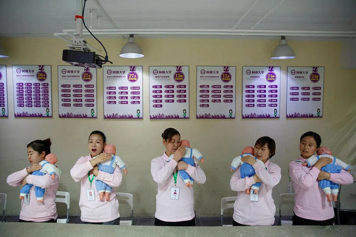 北京一所家政培训学校的学生在用玩具娃娃学习如何照看婴儿。（路透社） 