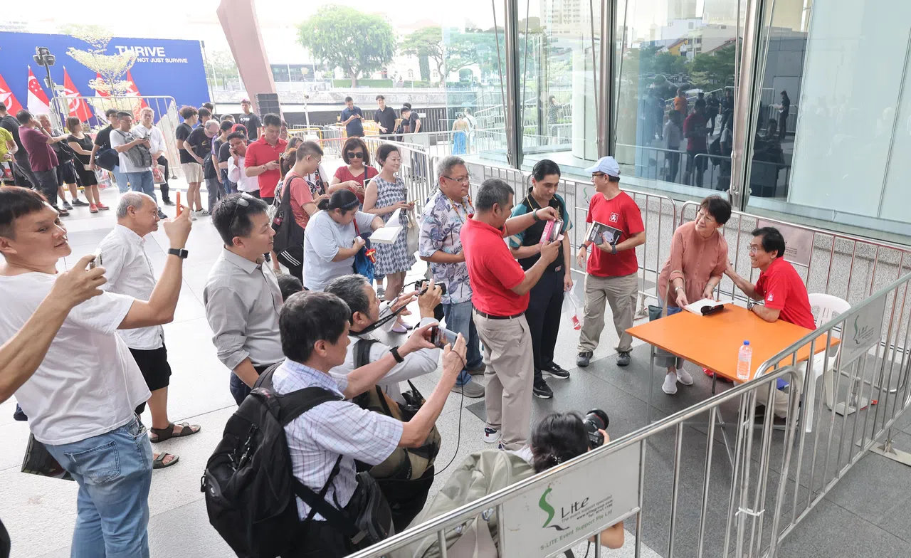 新加坡民主党秘书长徐顺全星期二在午间群众大会现场，举办签书活动，并与选民互动、合影。（唐家鸿摄）