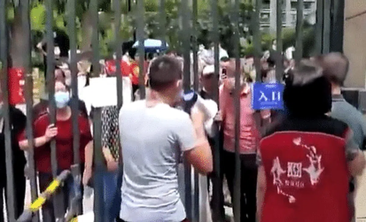 成都市龙泉驿区金茂悦龙山小区居民9月5日地震后想要避险，发现大门被锁。门外的防疫人员还拿起大喇叭喊话，要求居民不得外出。（视频截图）