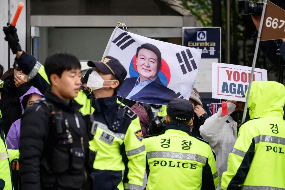 韩国一些民众星期一在首尔中央地方法院外手持前总统尹锡悦的肖像声援尹锡悦，警方在旁维持秩序。（法新社）