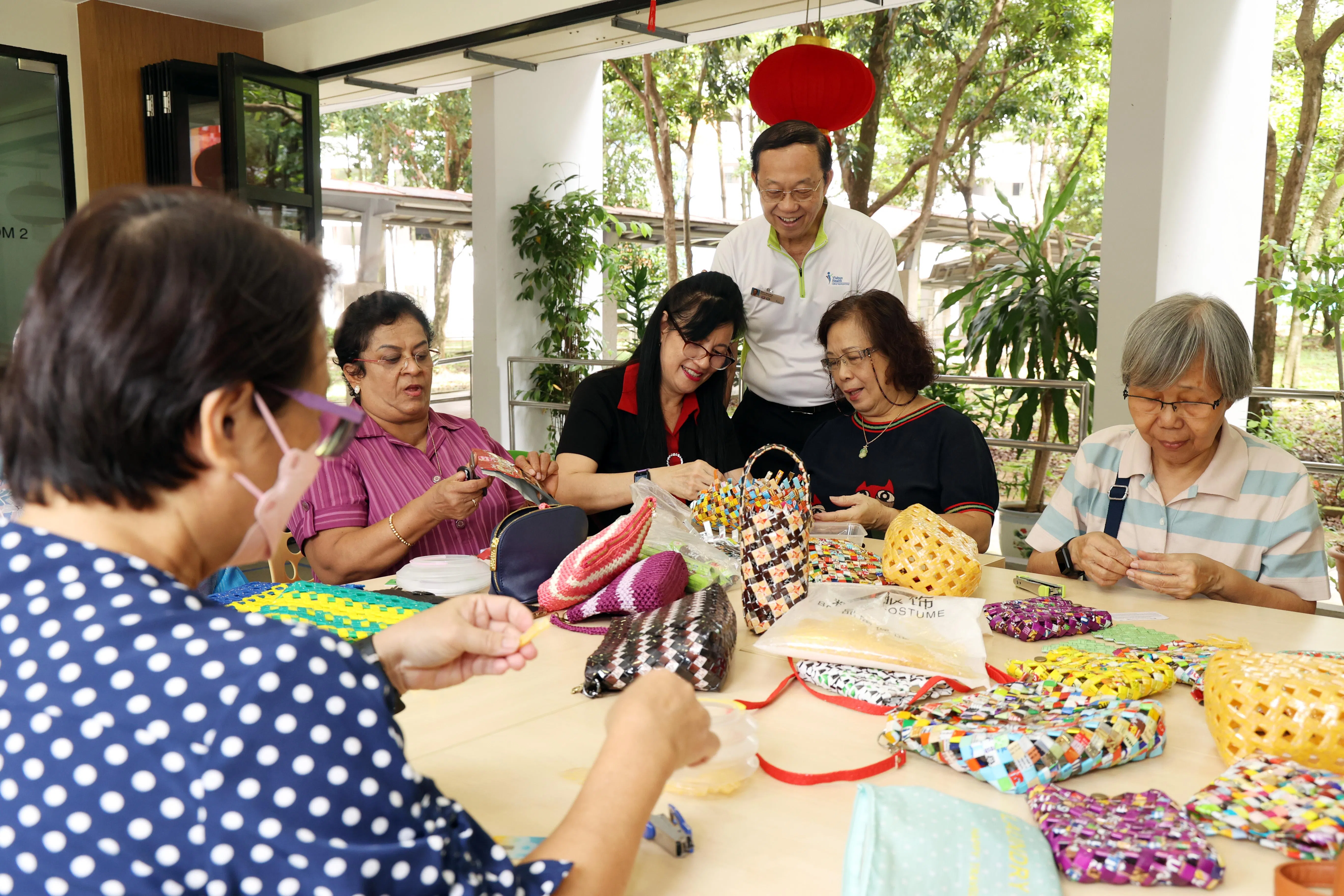 蔡丽金（坐着右三）教得开心，学员也学得愉快，难怪68岁的中心经理胡耀家（站立者）无意退休。（邝启聪摄）