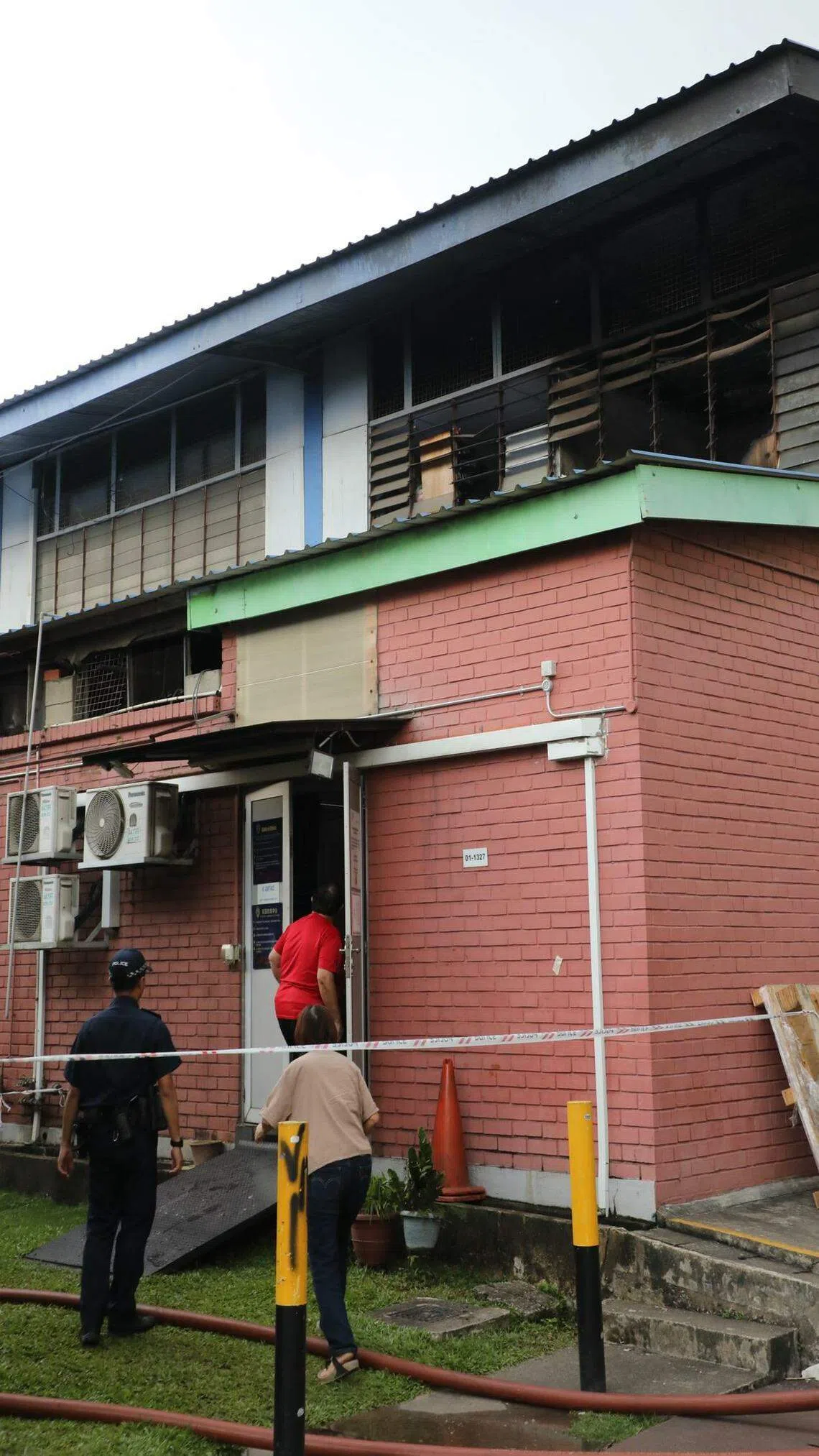 警方封锁事发地点的后巷，二楼百叶窗焦黑剥落，员工进入店内查看情况。（邝启聪摄）