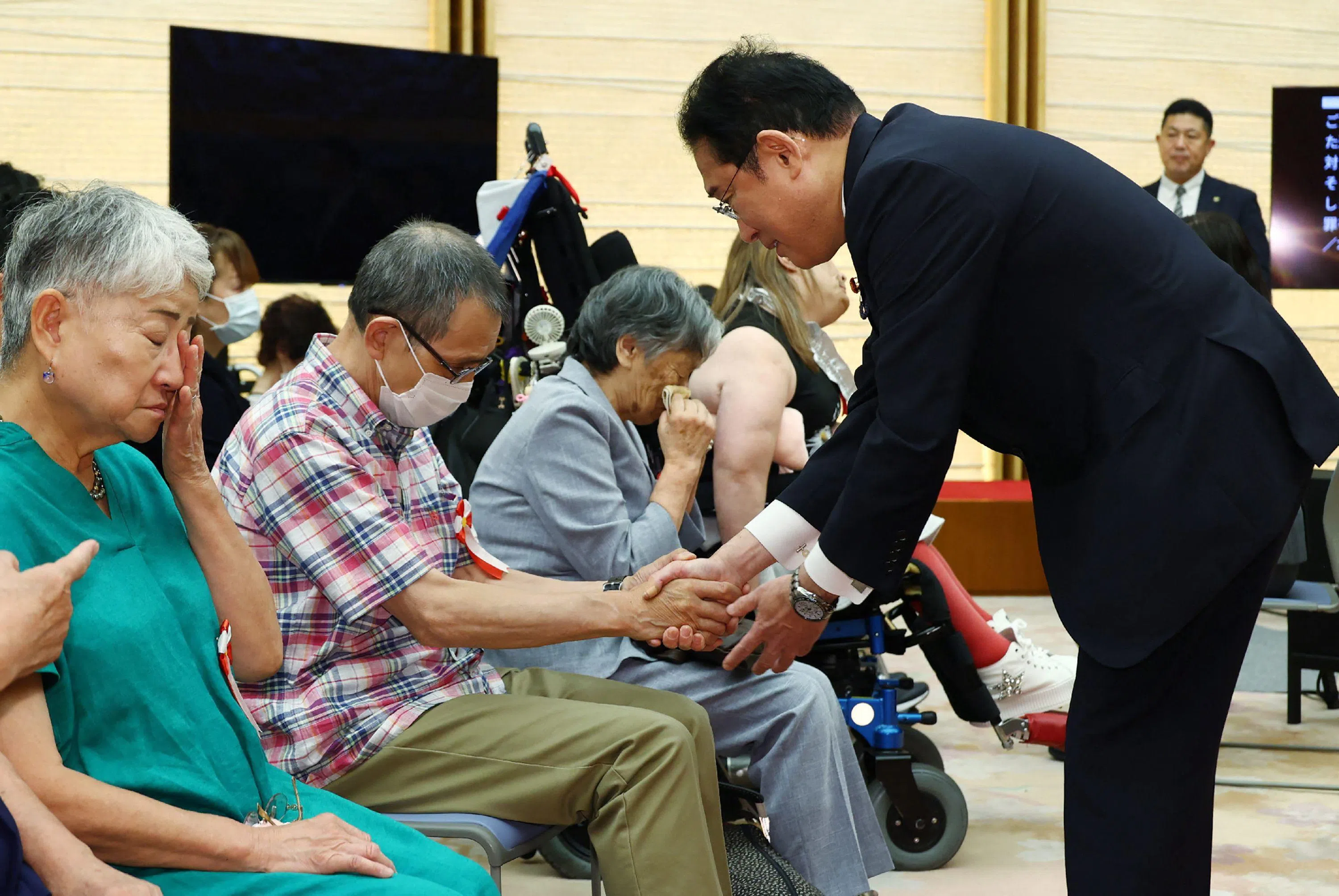 超过130名原告、辩护团队和支持者等参加了会晤。原告方向岸田（右）提交了全面解决要求书，要求尽快制定补偿法、实施面向防止问题再次发生的受害验证等。图为岸田与原告握手致歉。（法新社）