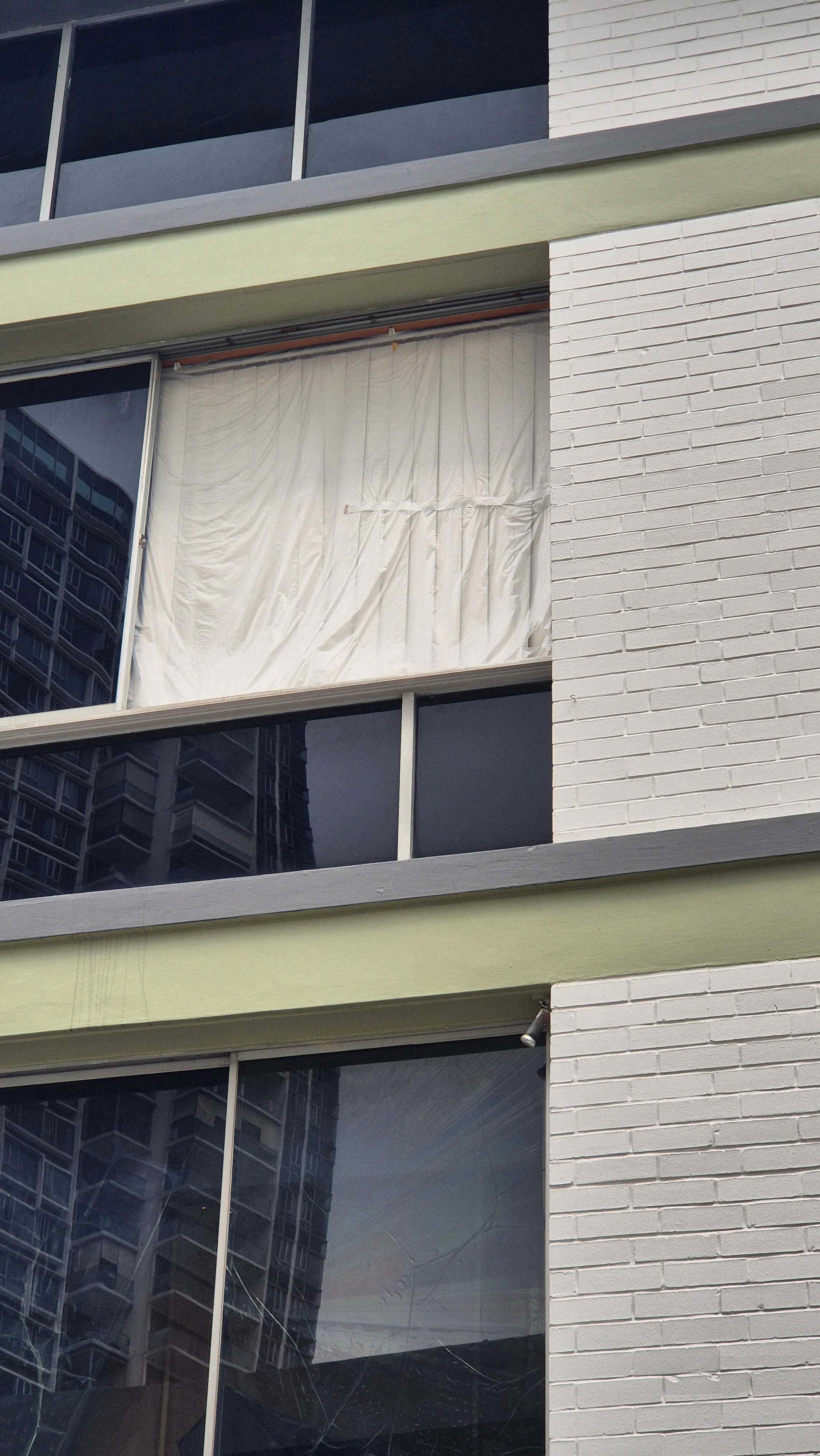 破损窗口暂时被布遮起。（吴伟国摄）