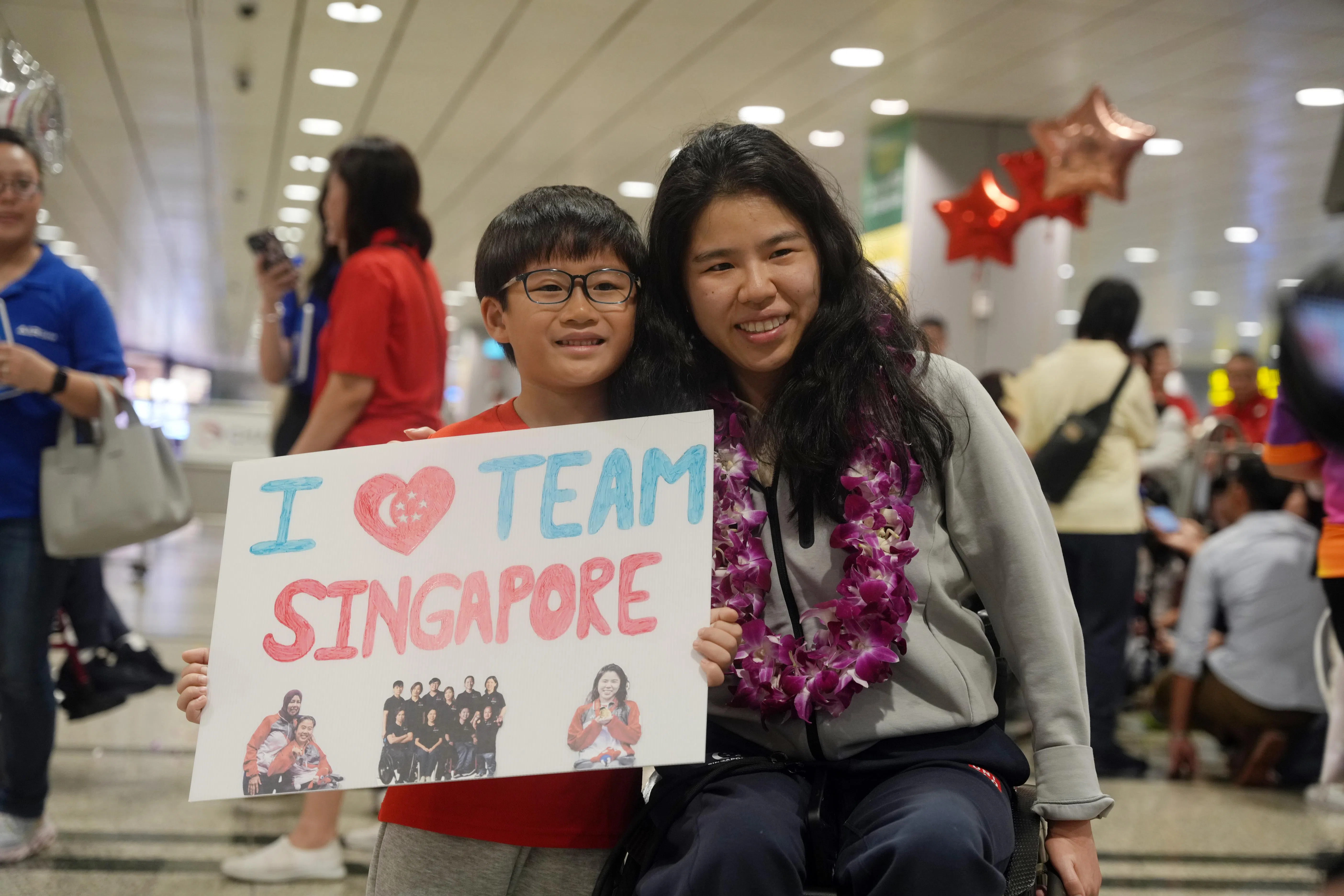 陈昱恺（左）手持“我爱新加坡团队”纸板和叶品秀合照。（谢智扬摄）