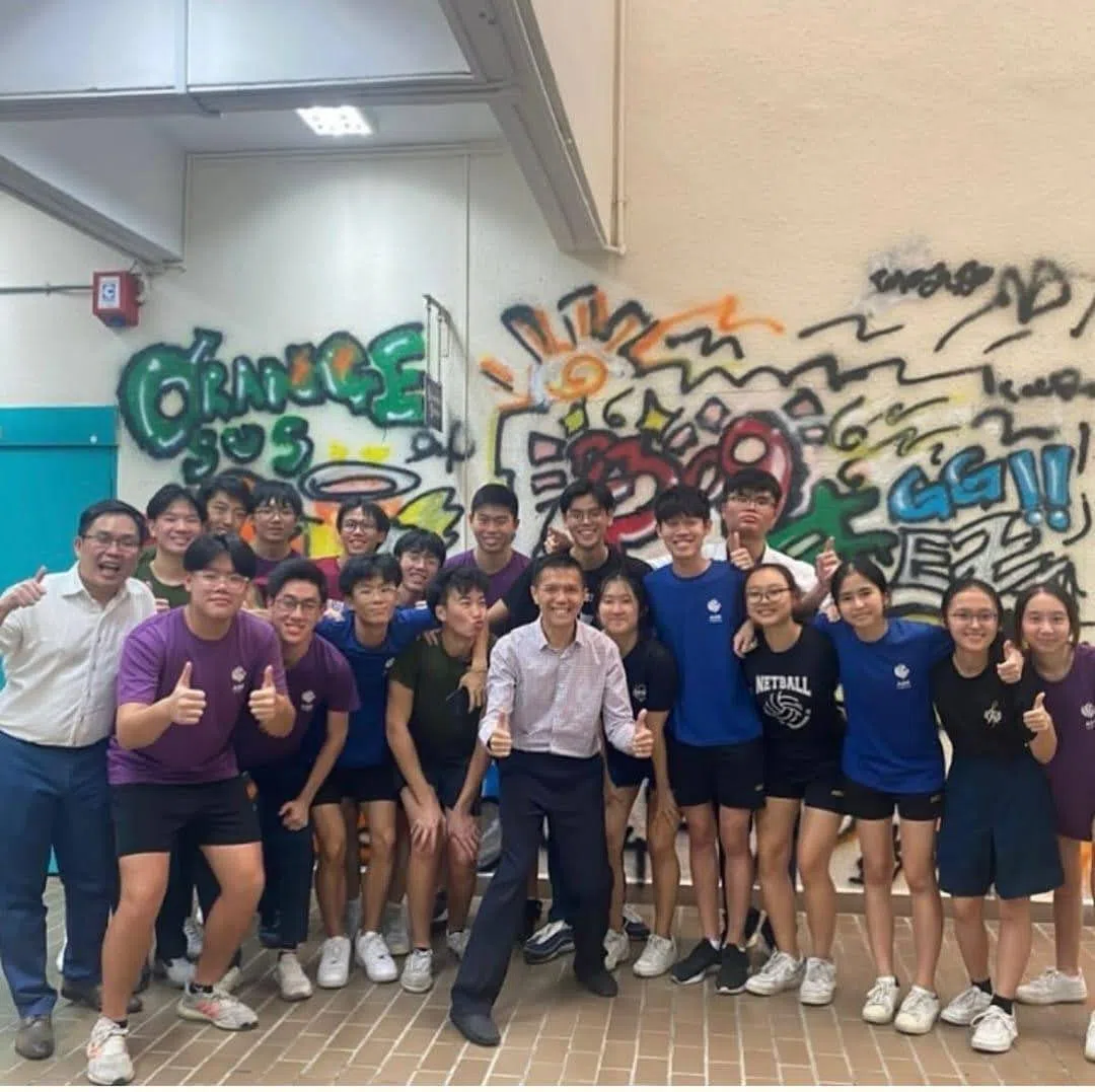 学生事务部门主任周世勇（左一） 、王有成院长（ 中）和学生们在喷绘的墙前竖起大拇指留影，记录校园生活中美好的一刻。（安德逊实龙岗初院提供）