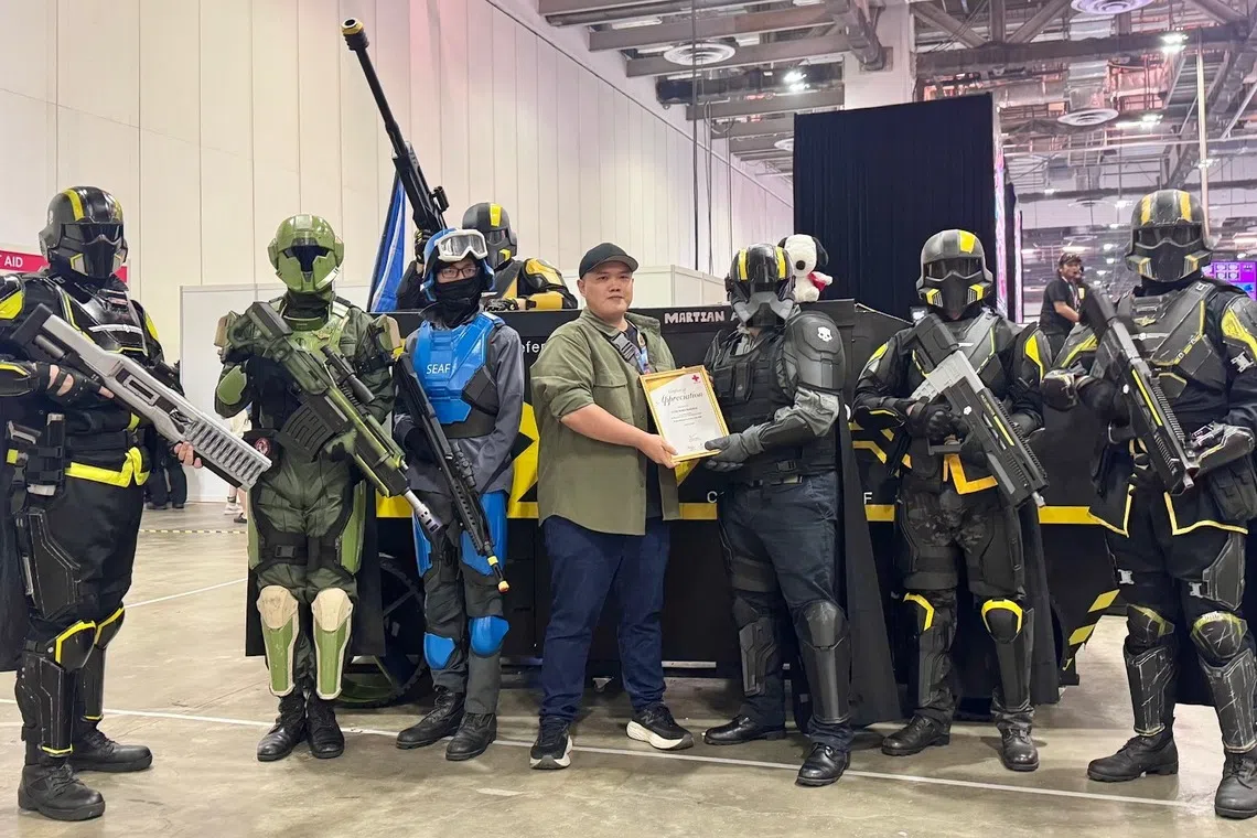 新加坡红十字会代表（左四）在新加坡动漫展期间，向《地狱潜兵2》玩家团体“第117突击营”成员颁发致谢牌。（受访者提供）